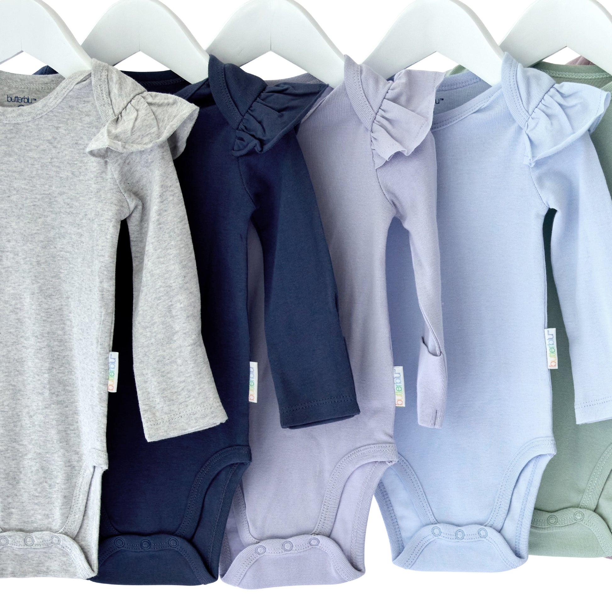 Row of baby onesies in various colors hanging on a rack.