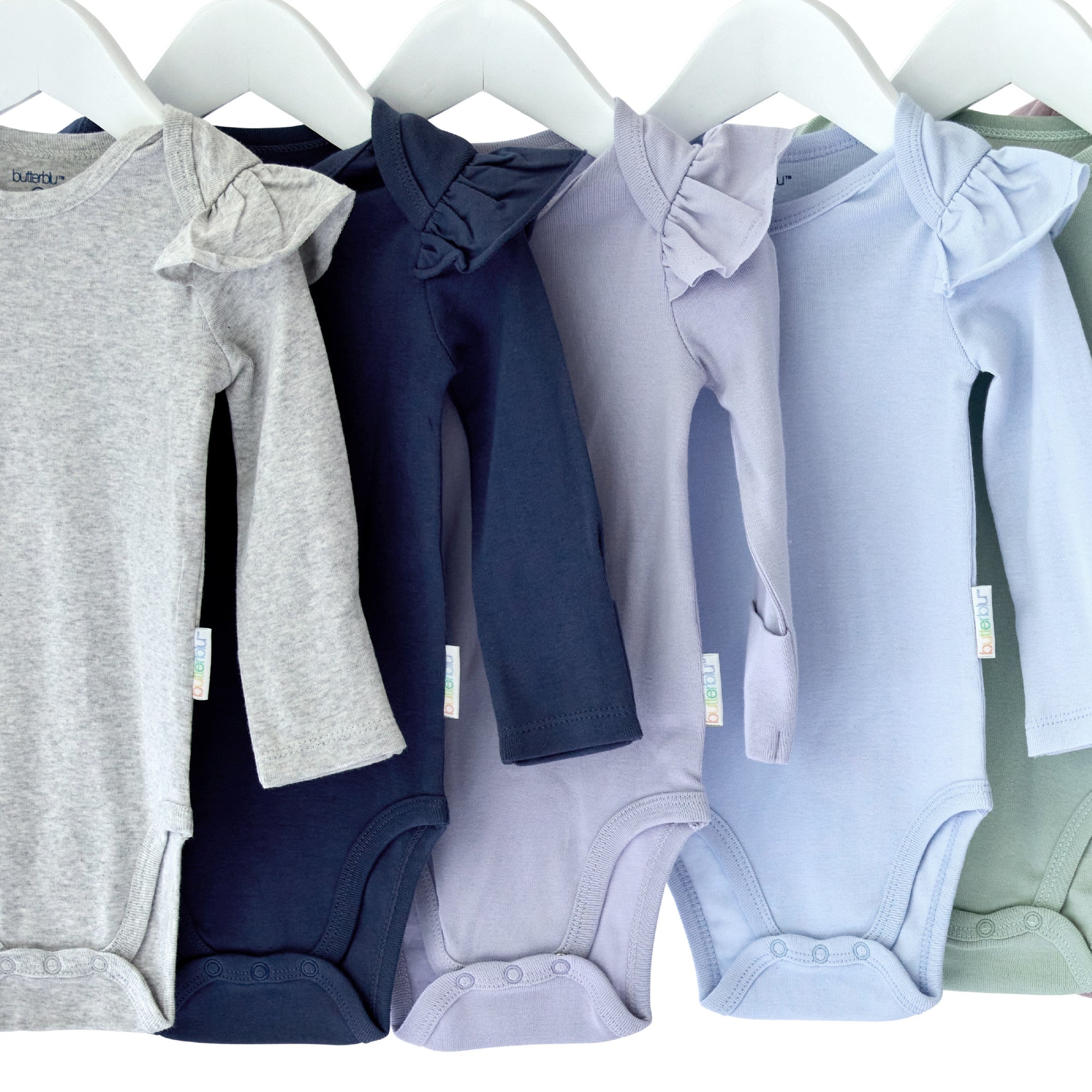Row of baby onesies in various colors hanging on a rack.