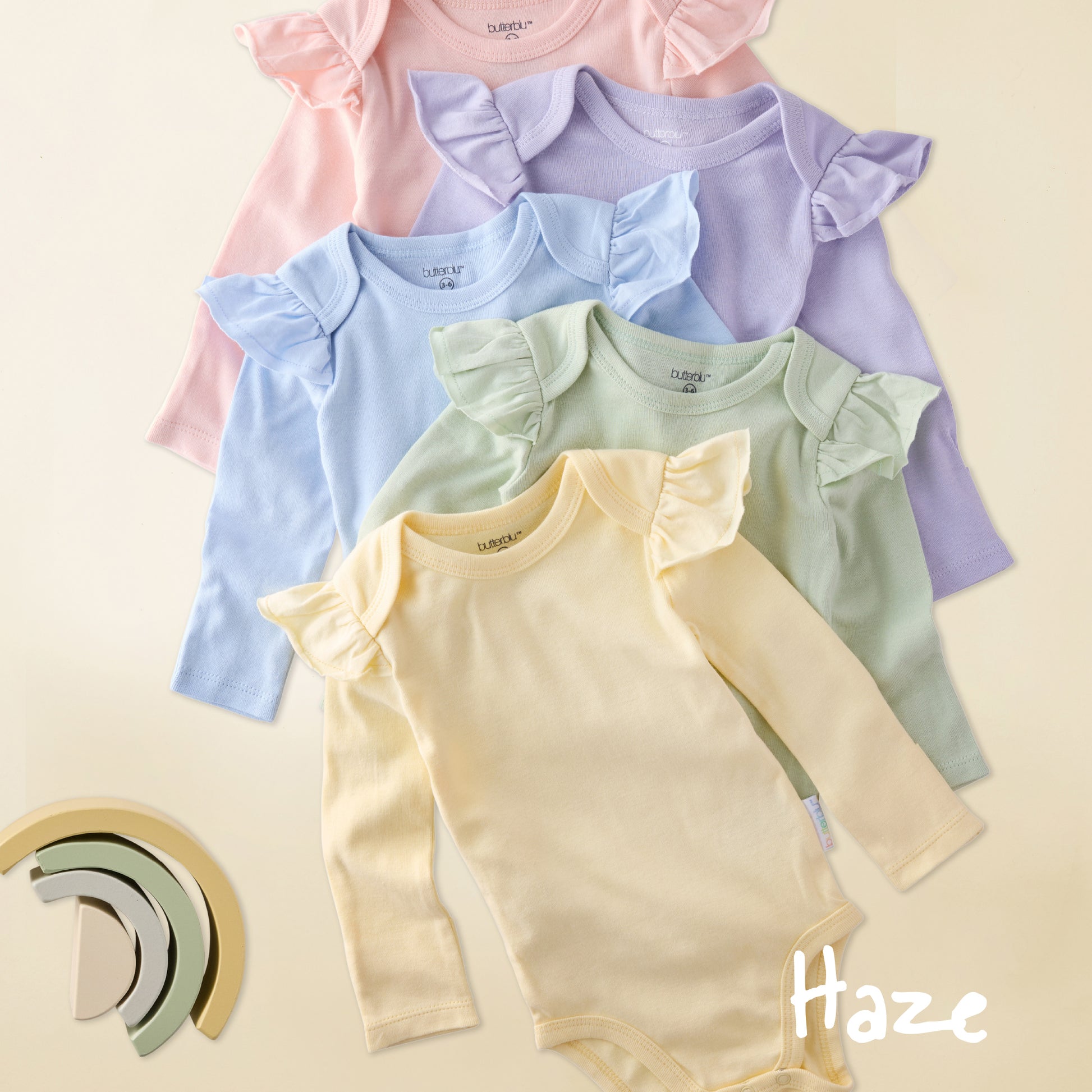 Set of colorful baby bodysuits with ruffled shoulders on a light background