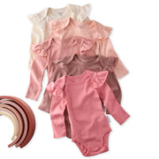 Set of baby bodysuits in various pink shades with ruffled shoulders on a white background.