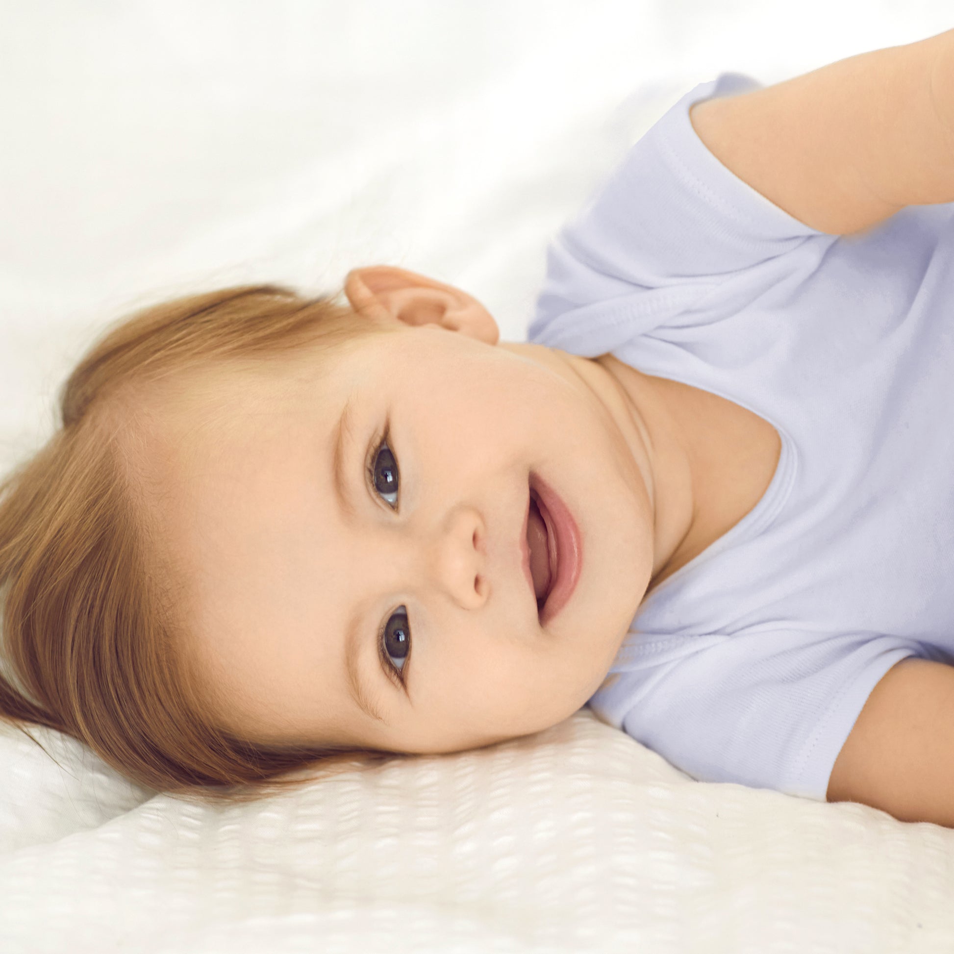 Child wearing a white shirt lying on a white surface