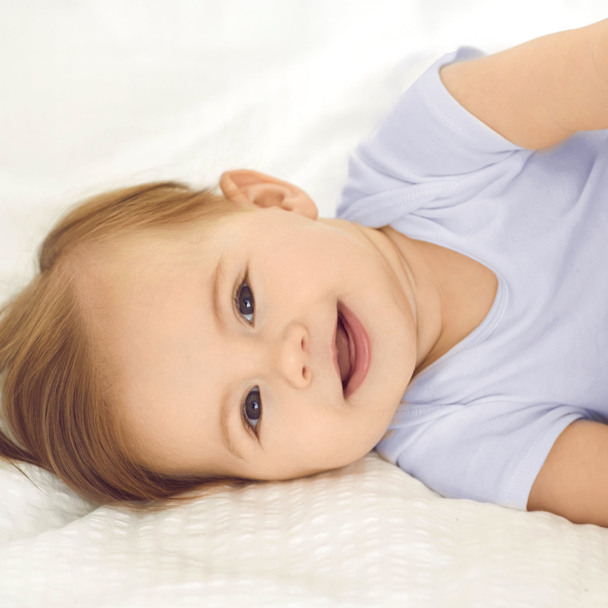 Child wearing a white shirt lying on a white surface