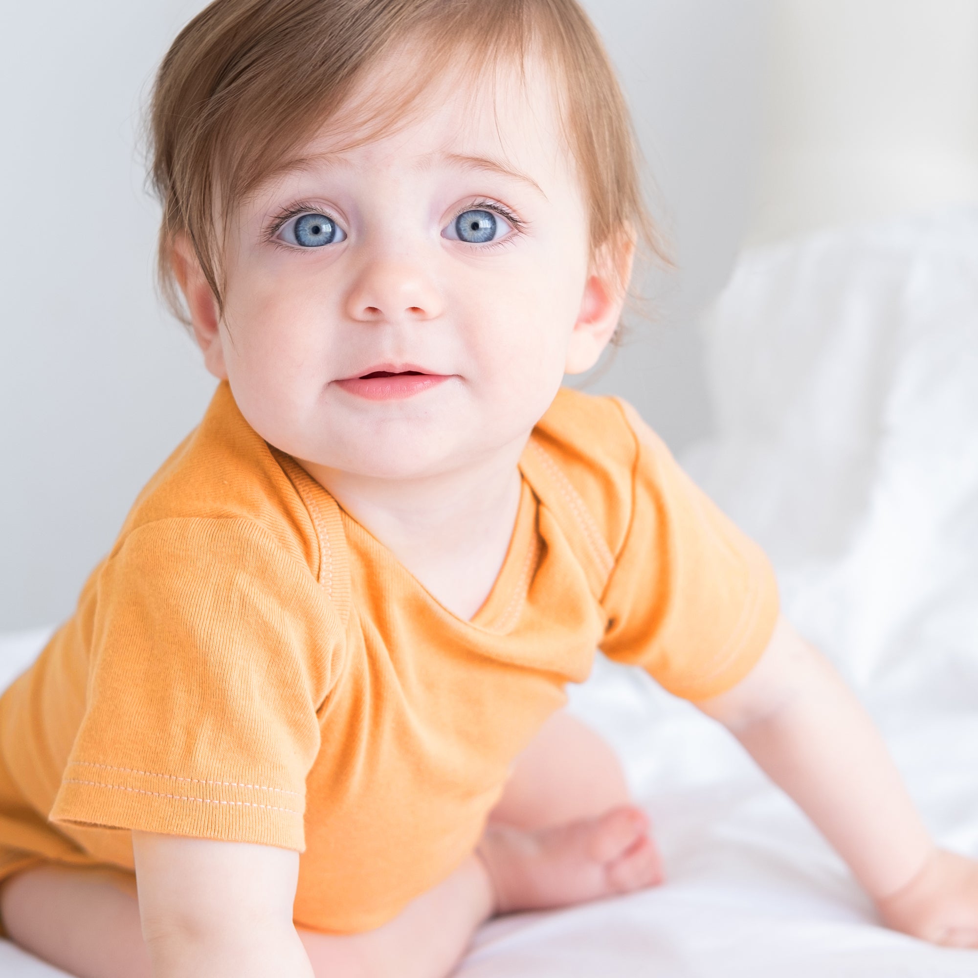 Child wearing an orange shirt on a white background