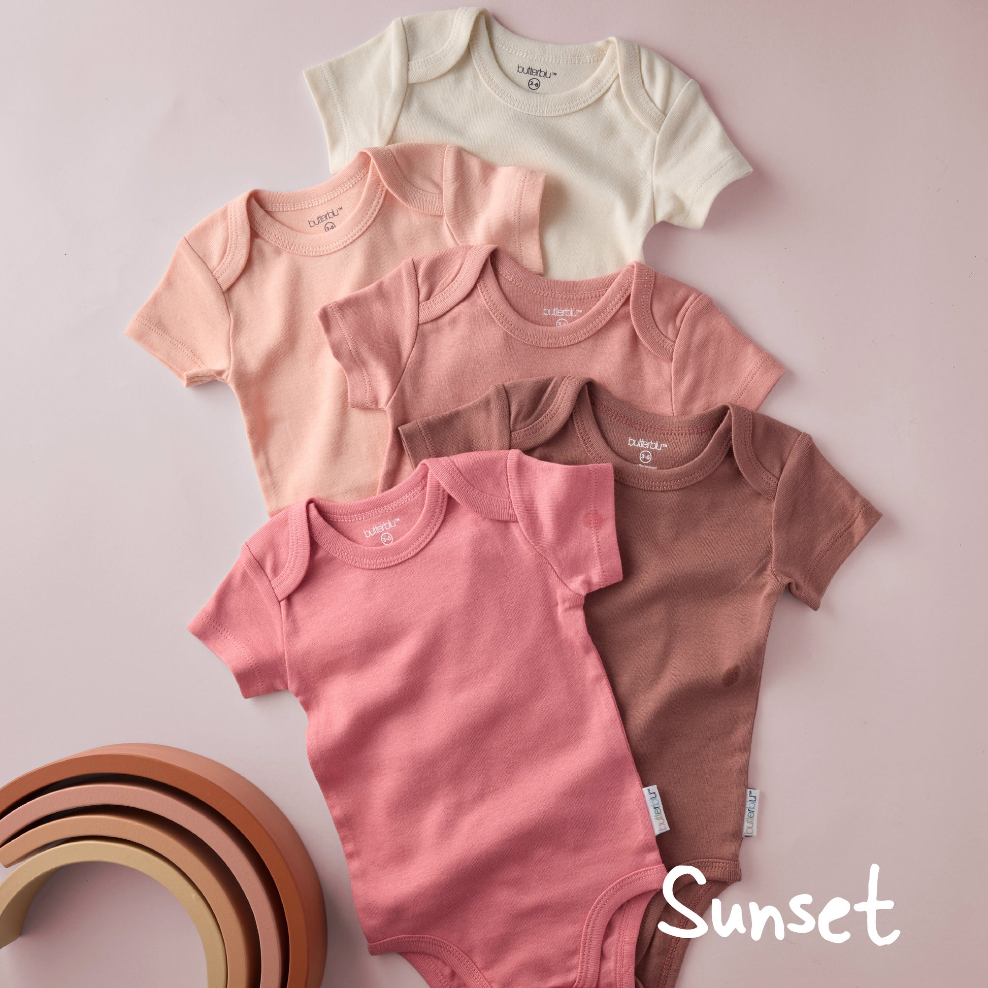 Set of baby bodysuits in various colors on a light pink background with 'Sunset' text.