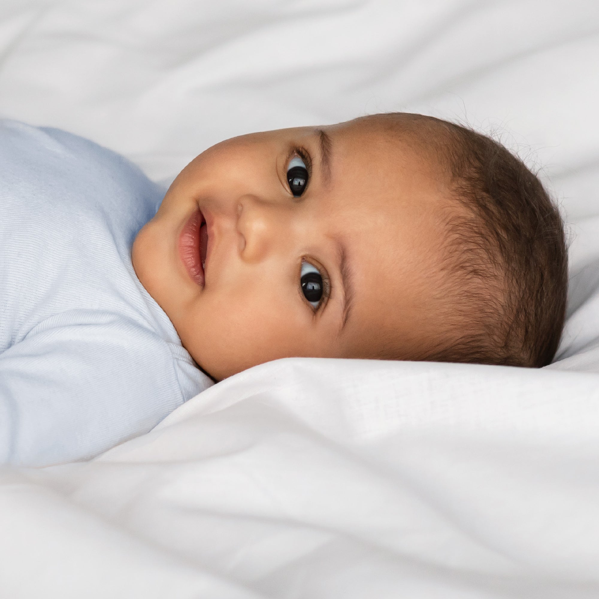 Baby lying on a white blanket with a soft focus background