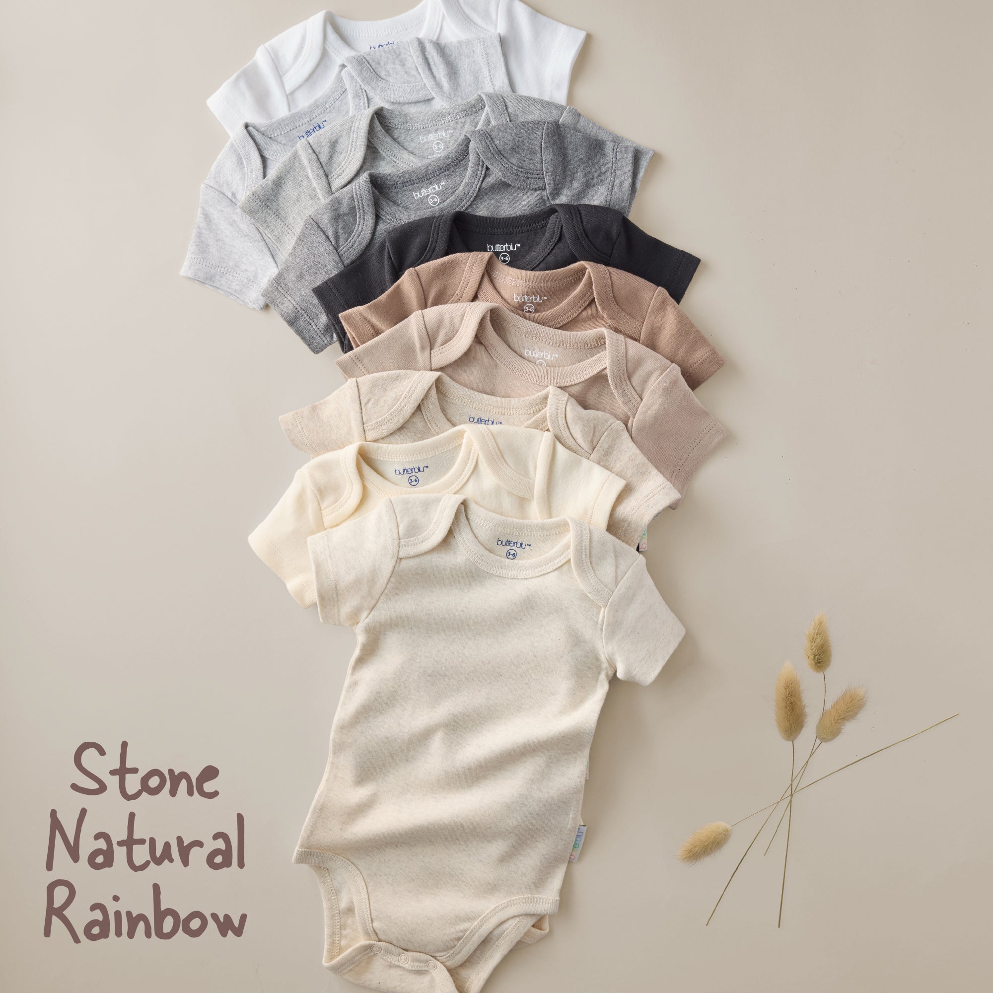 Row of baby onesies in various colors on a beige background