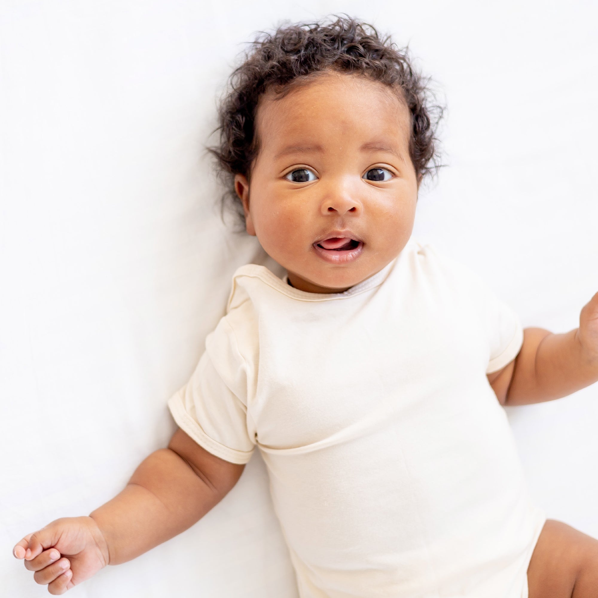 Baby wearing a white onesie on a white background
