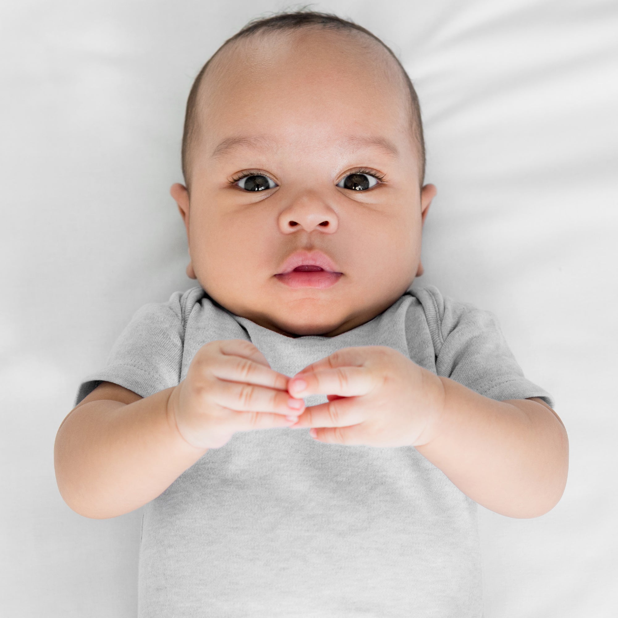 Baby wearing a gray onesie on a white background