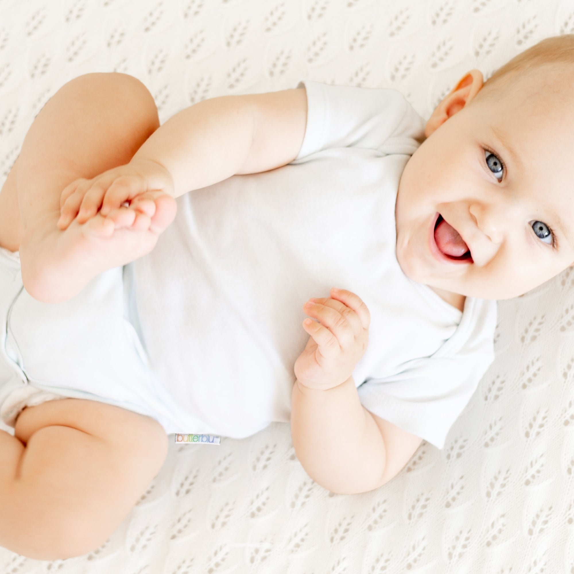 Baby in a white onesie lying on a textured surface