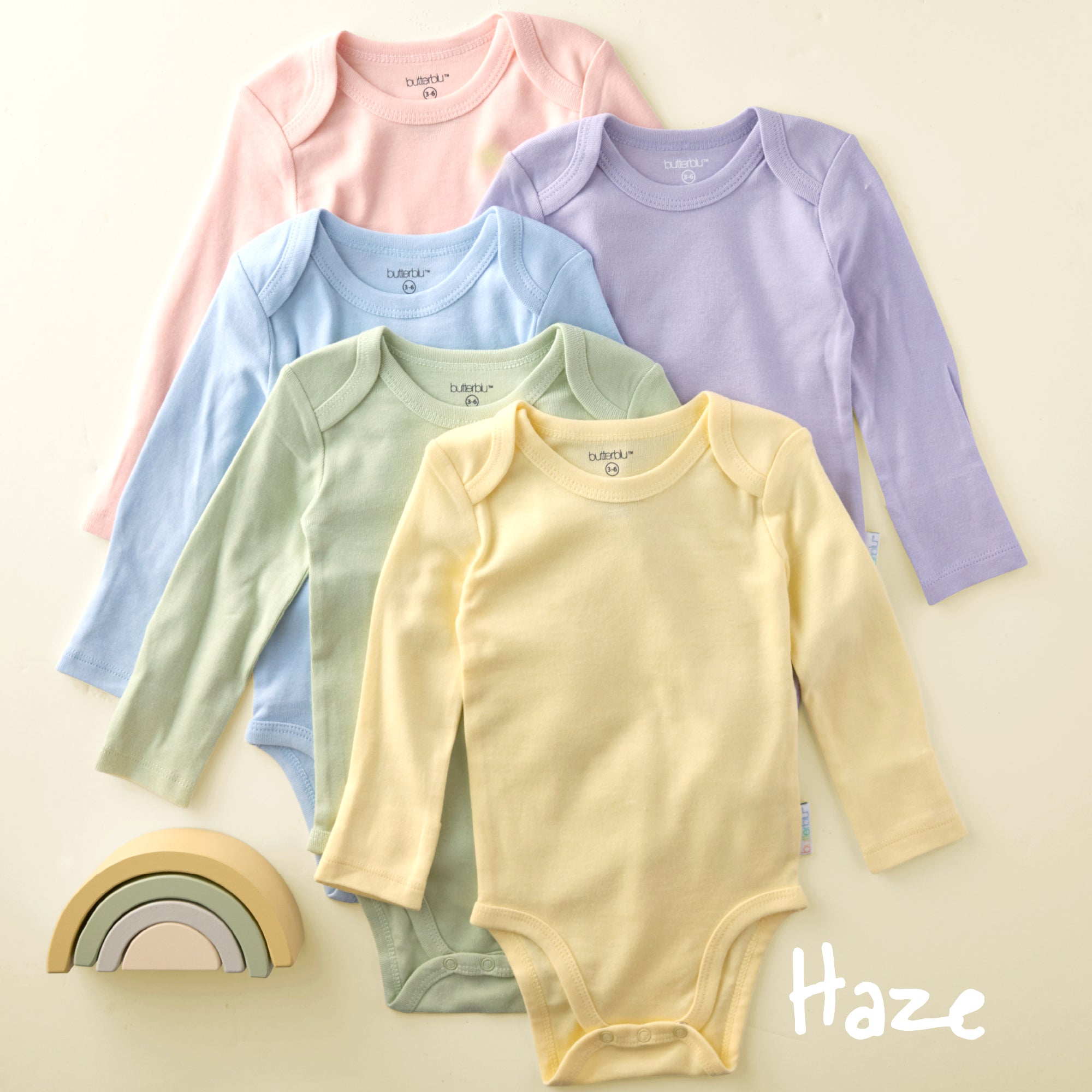 Five baby bodysuits in pink, blue, green, and yellow on a beige background with 'Haze' branding.