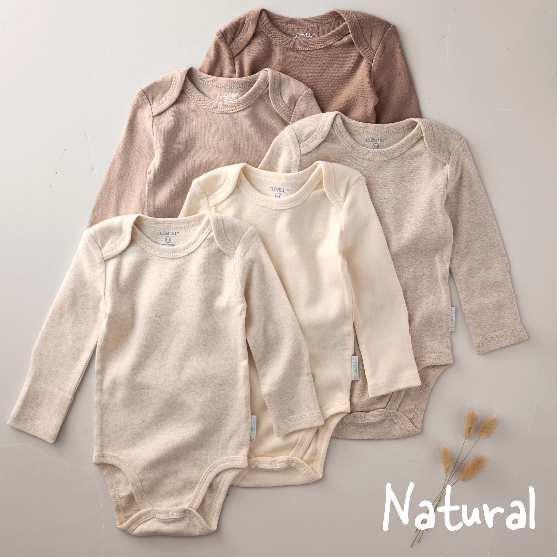 Four baby bodysuits in beige and brown on a gray background with 'Natural' text.