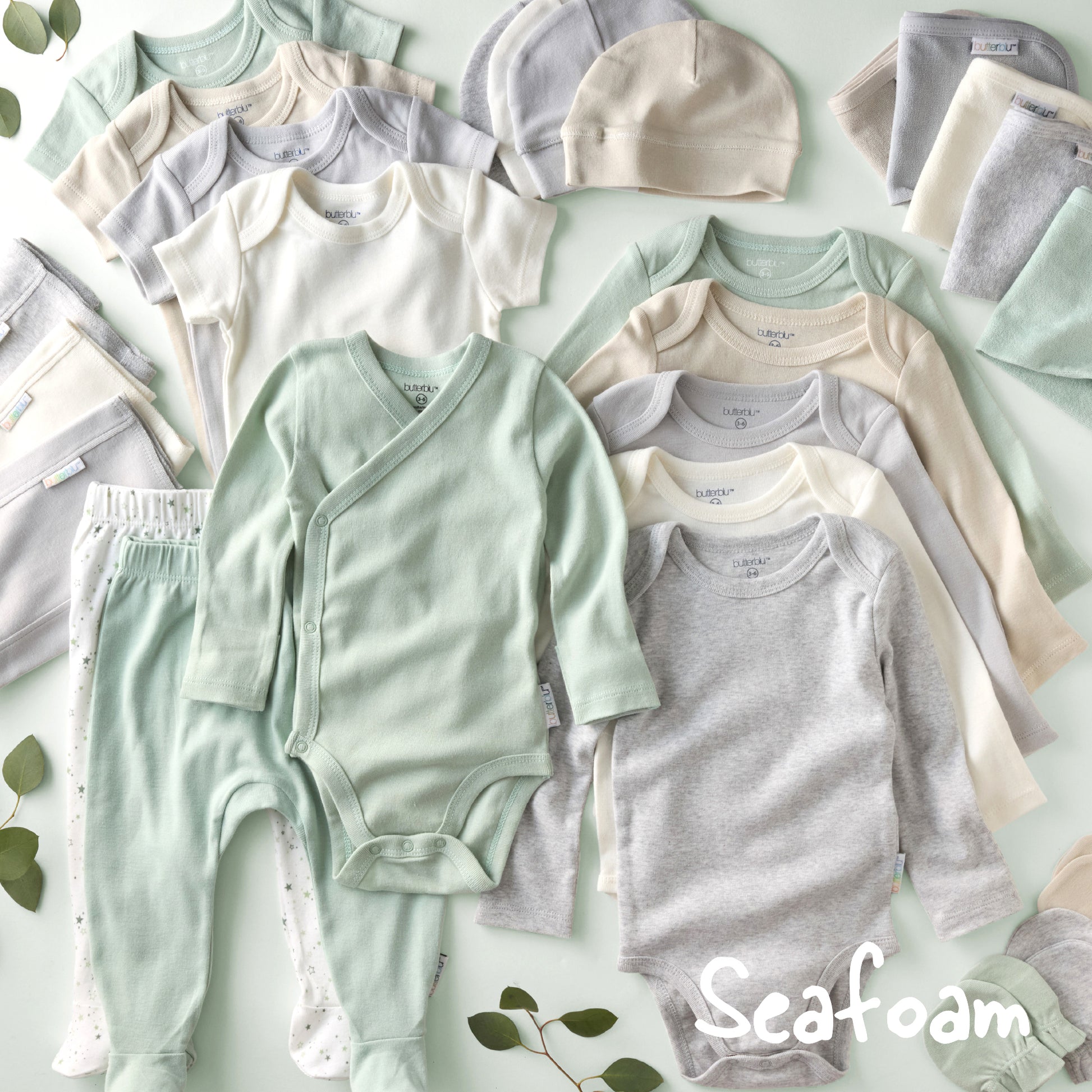 Collection of baby clothing in seafoam green, gray, and white on a light green background with 'Seafoam' branding.