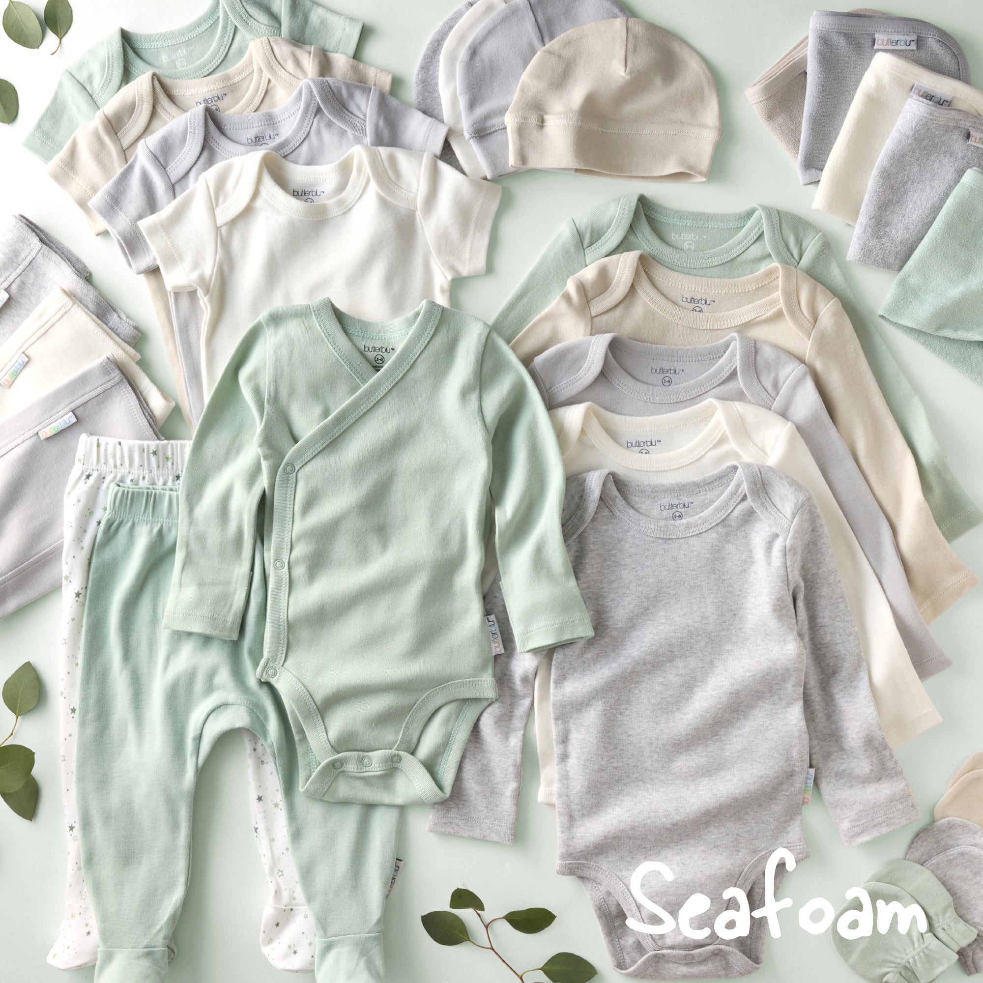 Collection of baby clothing in seafoam green, gray, and white on a light green background with 'Seafoam' branding.