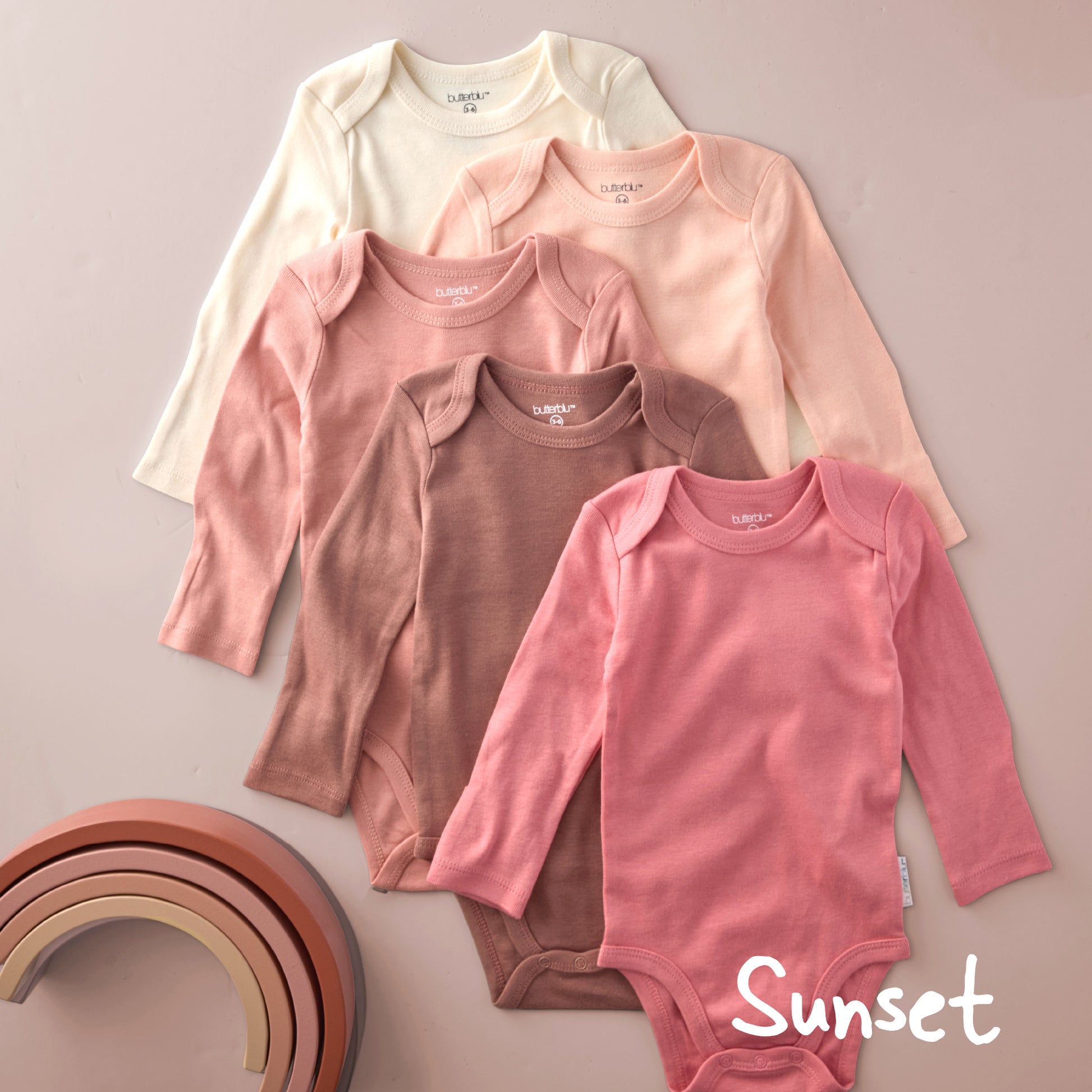 Set of baby bodysuits in various pink shades on a beige background with 'Sunset' text.