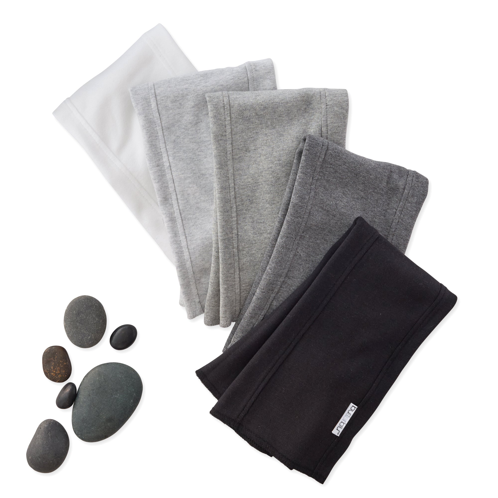 Set of folded gray and black towels with stones on a white background