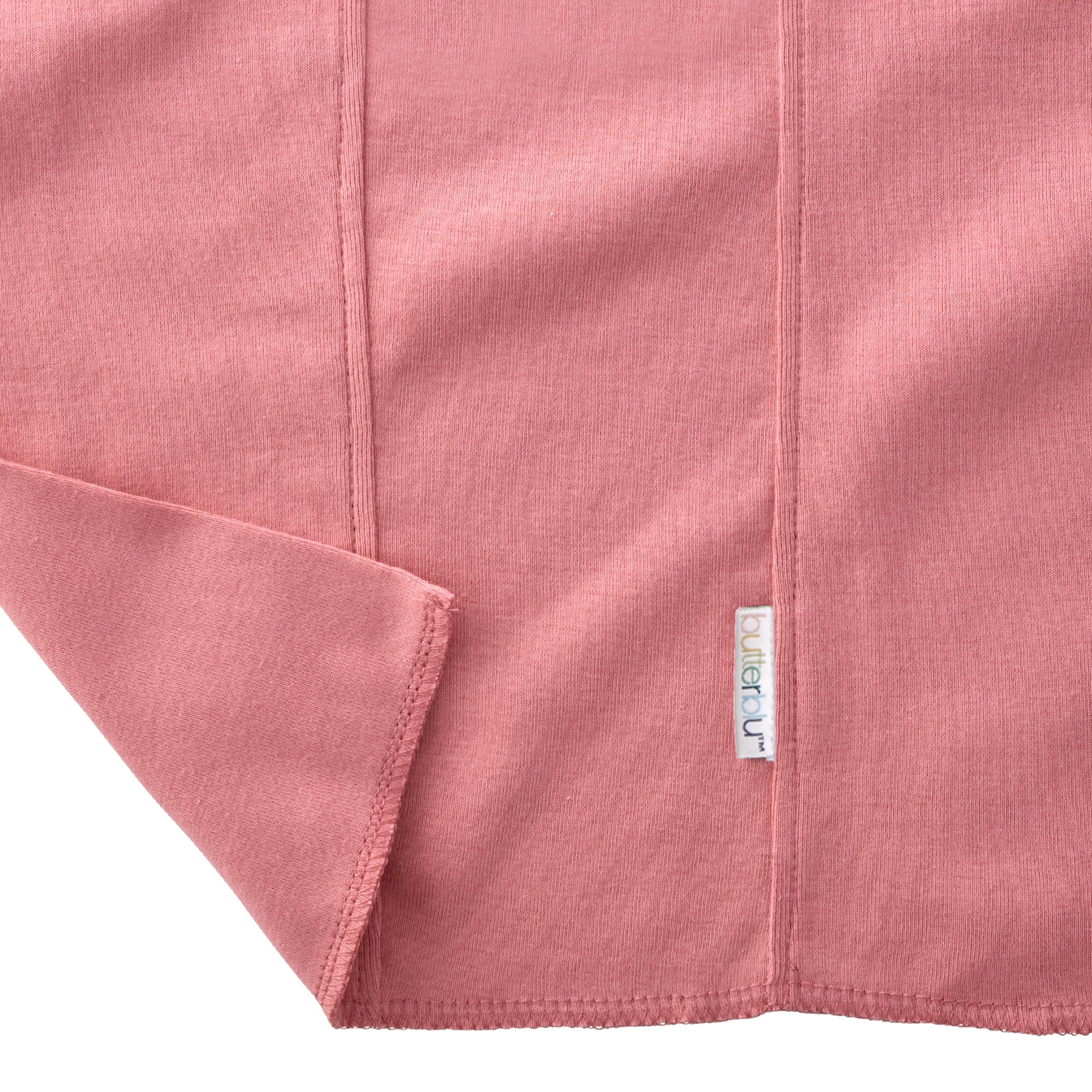 Close-up of a pink fabric with a visible brand label on a white background