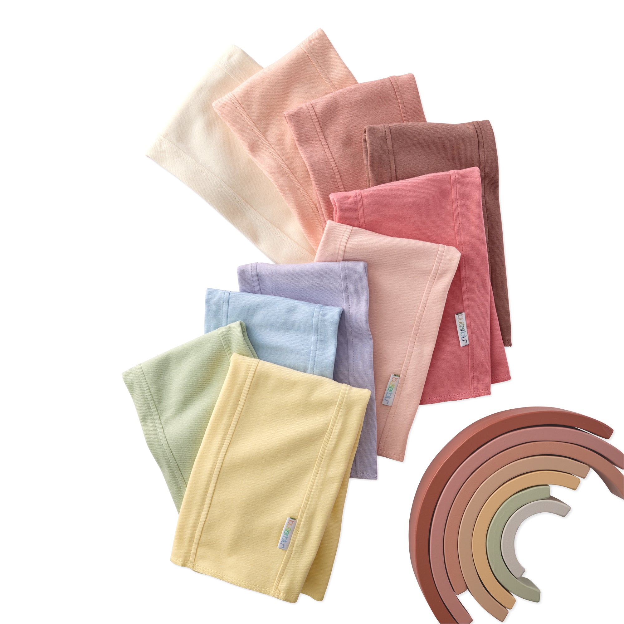 Set of folded colorful baby pants with a wooden toy on a white background