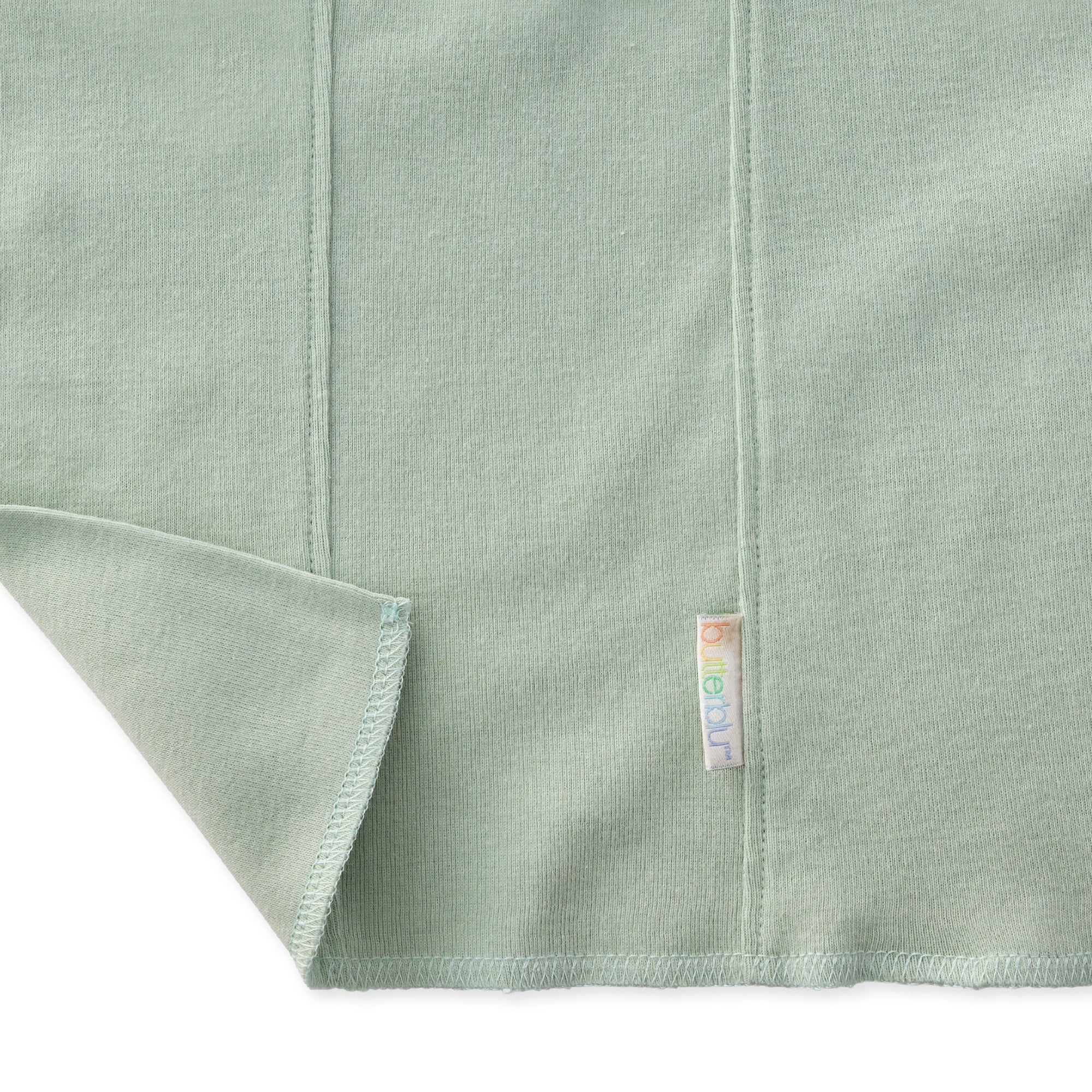 Close-up of a light green fabric with a brand label on a white background