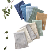 Set of folded towels in various colors on a white background with green leaves.