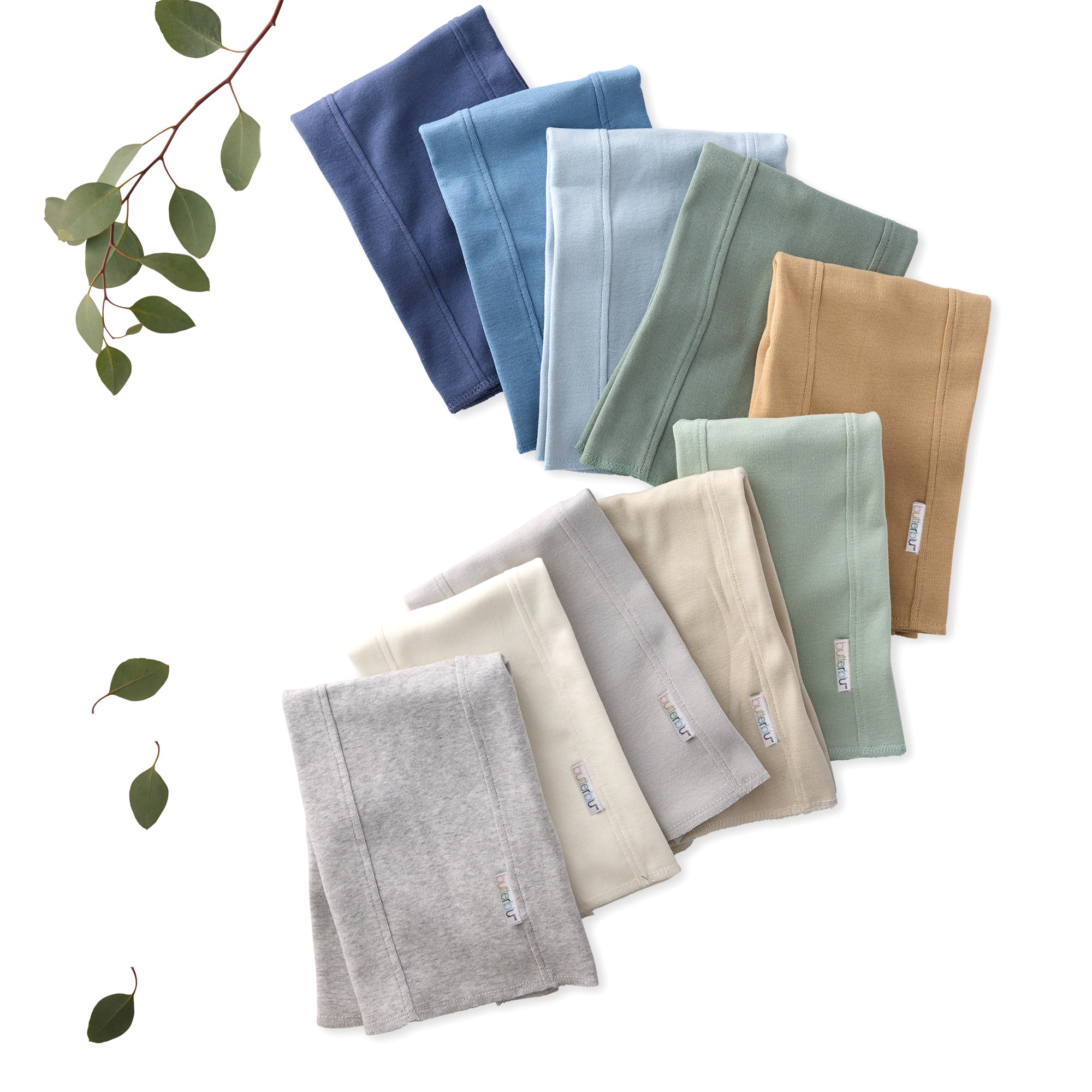 Set of folded towels in various colors on a white background with green leaves.