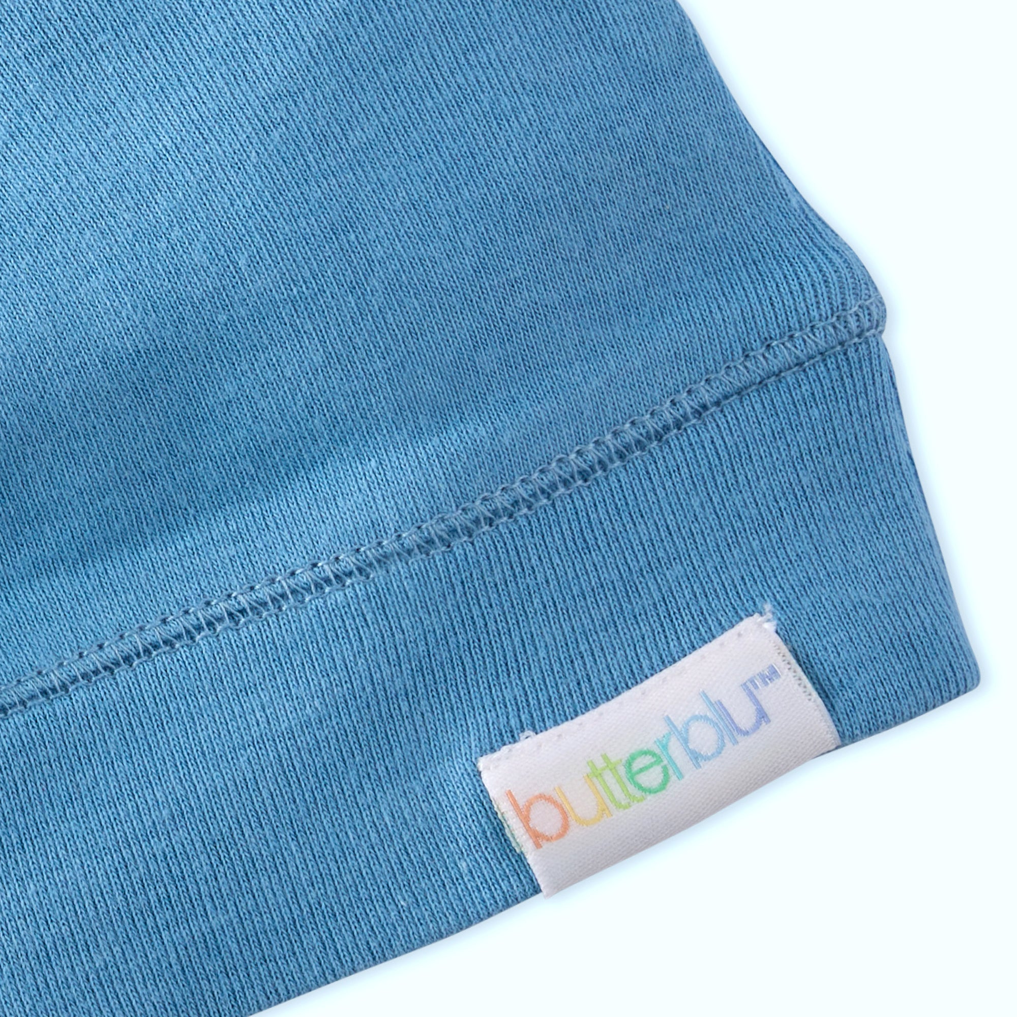 Close-up of a blue fabric with a 'butterblu' label on a white background