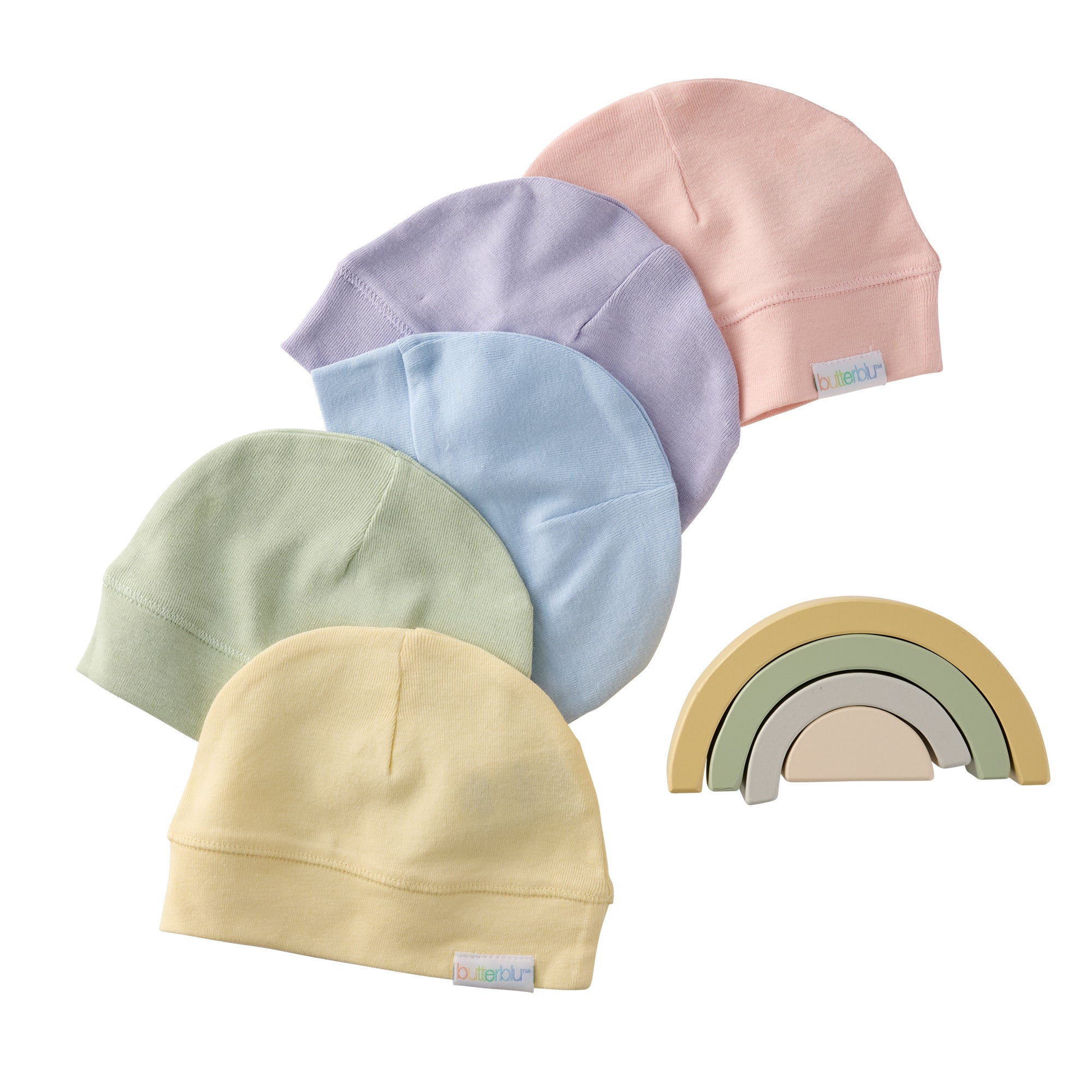 Set of pastel-colored baby hats and a rainbow toy on a white background
