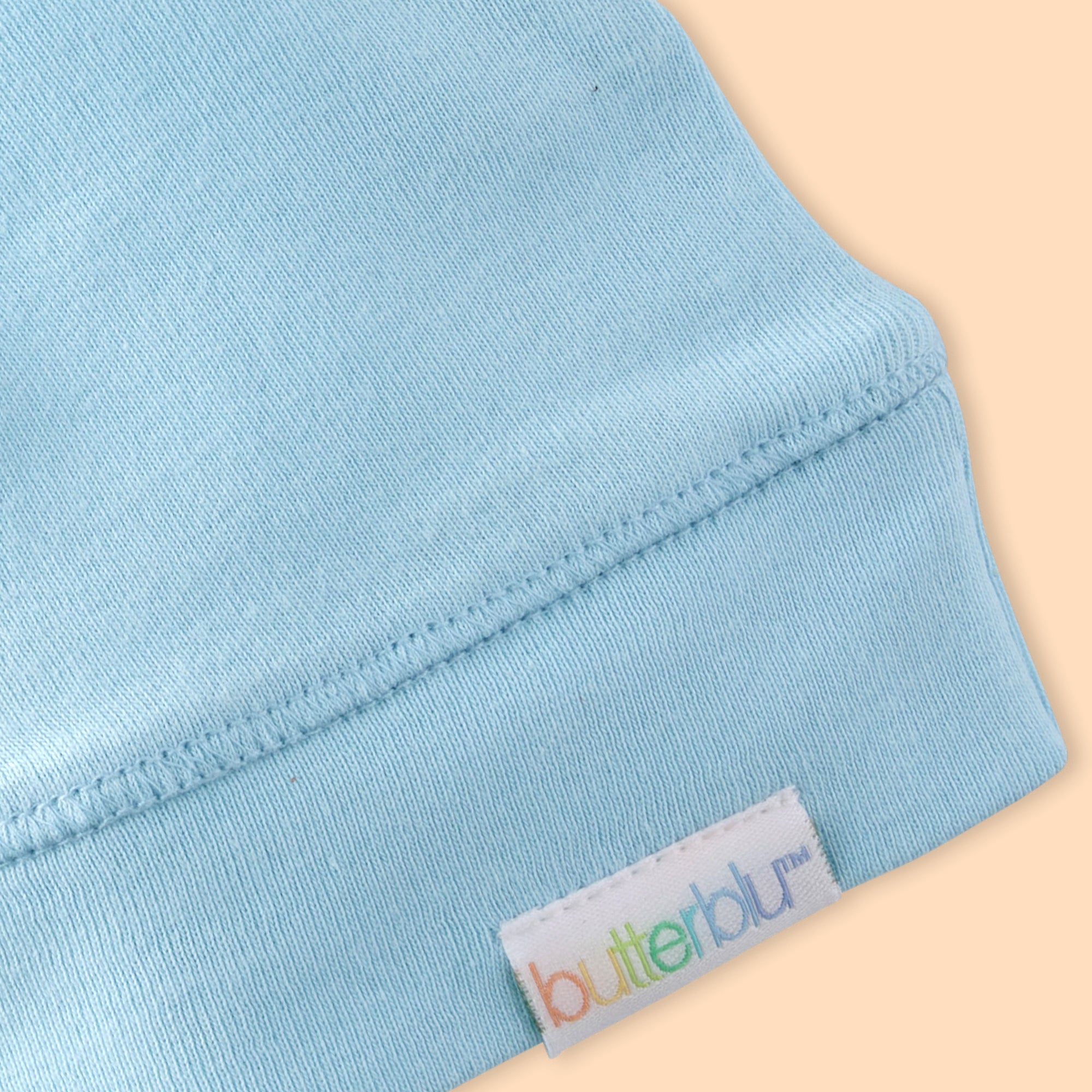 Close-up of a light blue fabric with a 'butterblu' label on a beige background