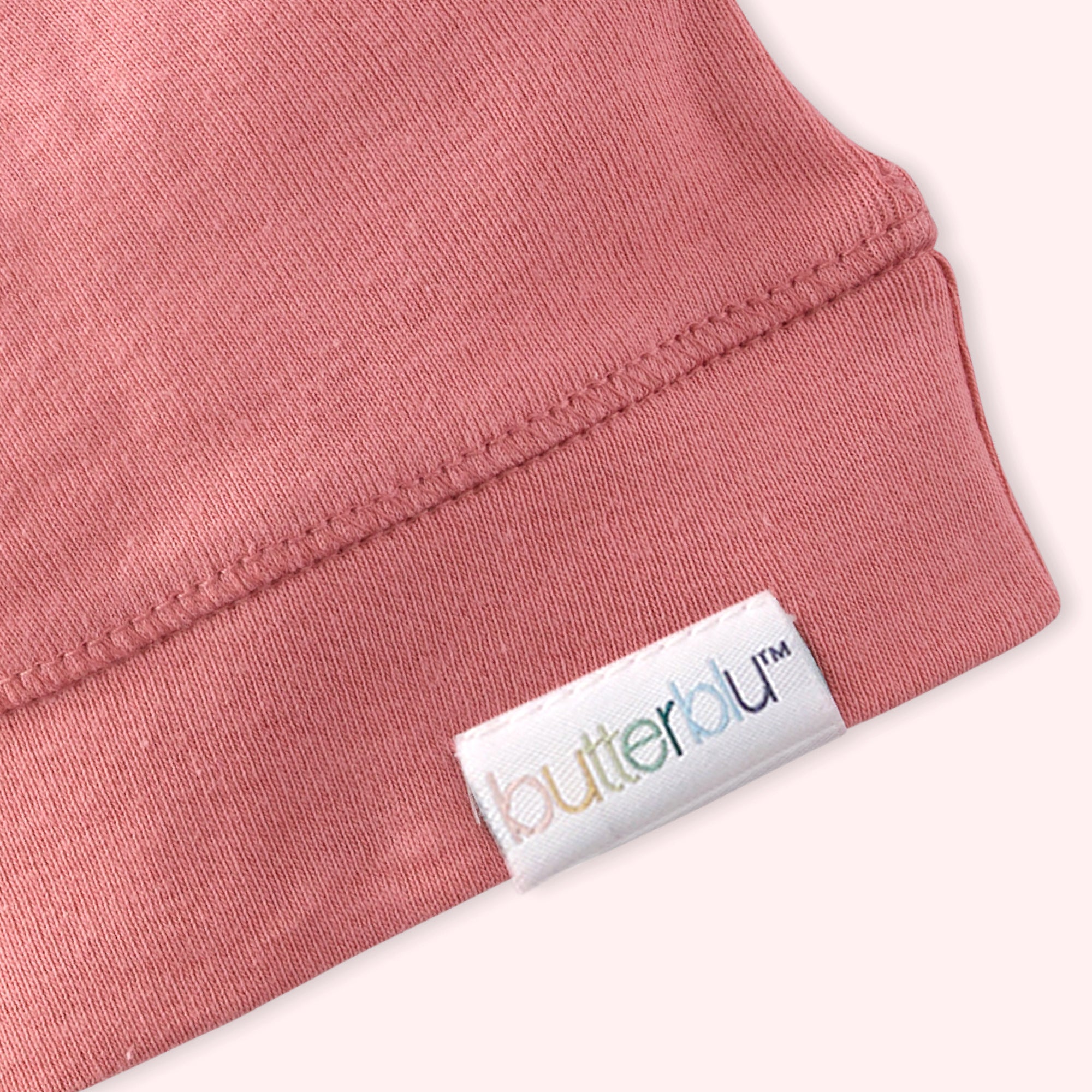 Close-up of a pink garment with a 'butterbu' label on a light background