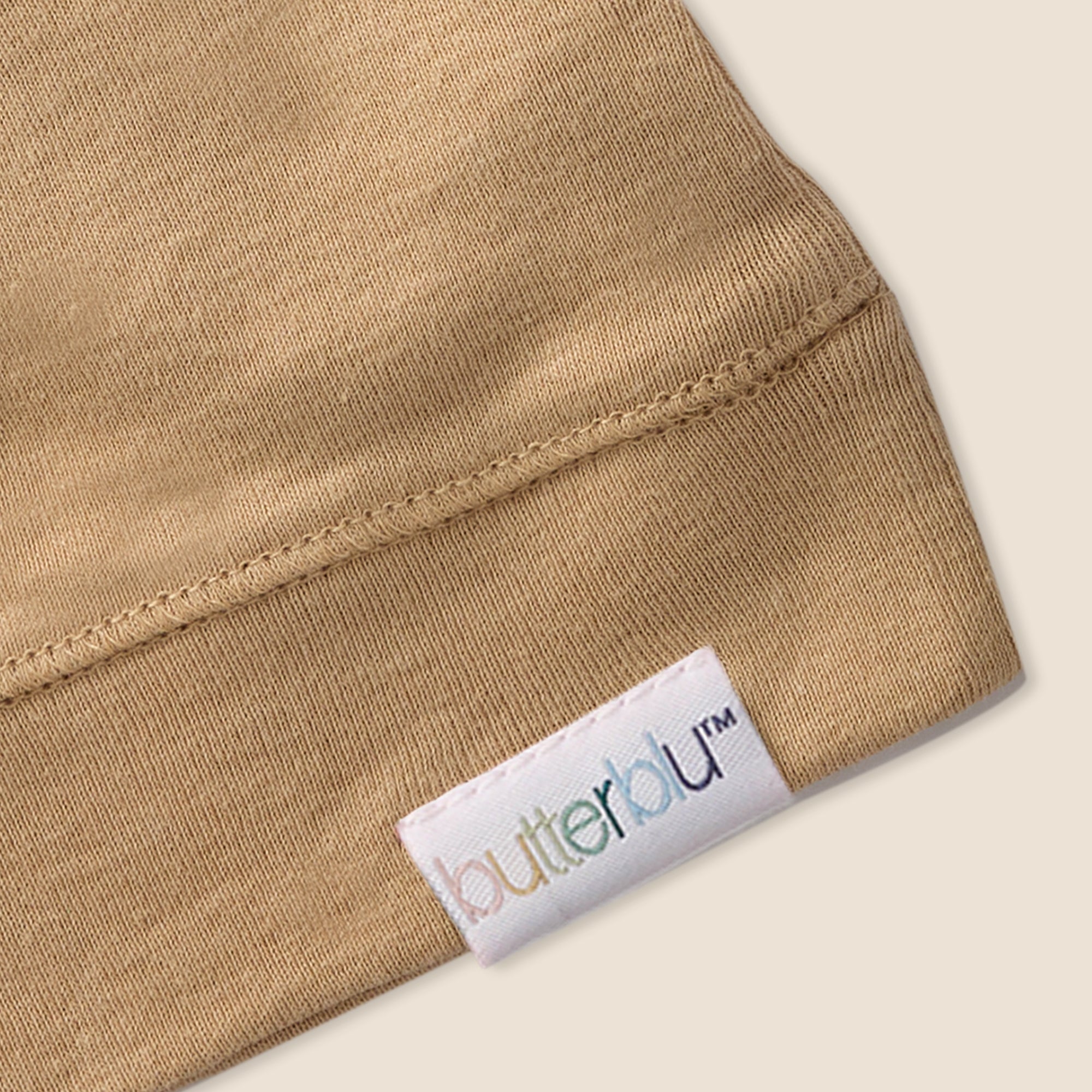 Close-up of a beige fabric with a 'butterblu' label on a light background