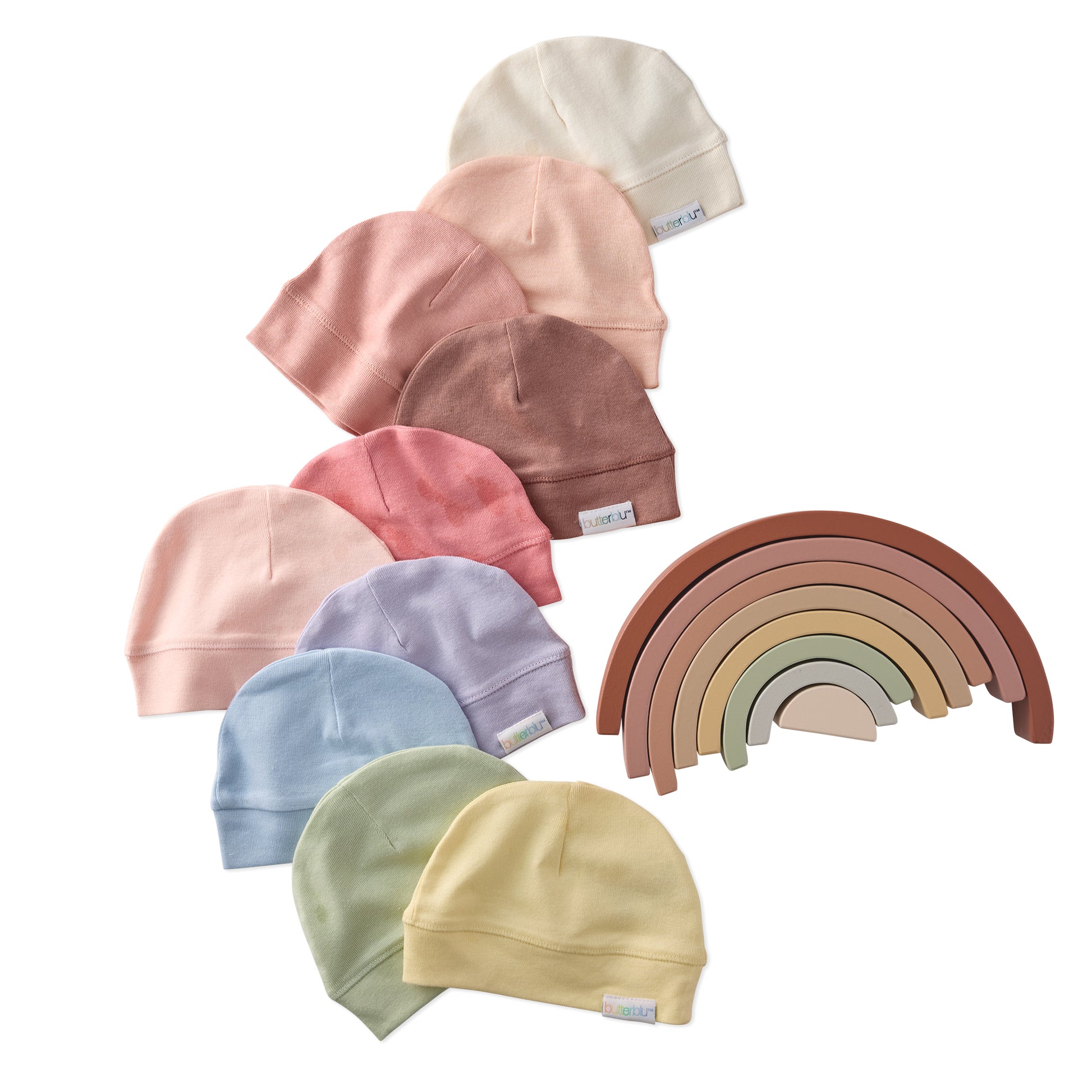 Set of colorful baby hats and a wooden rainbow toy on a white background