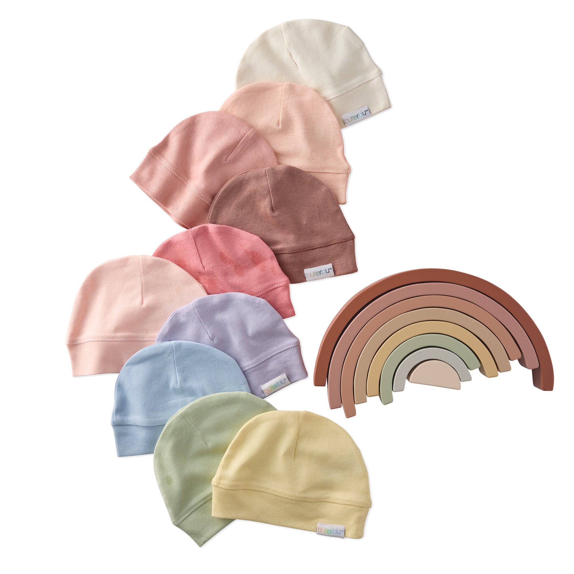 Set of colorful baby hats and a wooden rainbow toy on a white background
