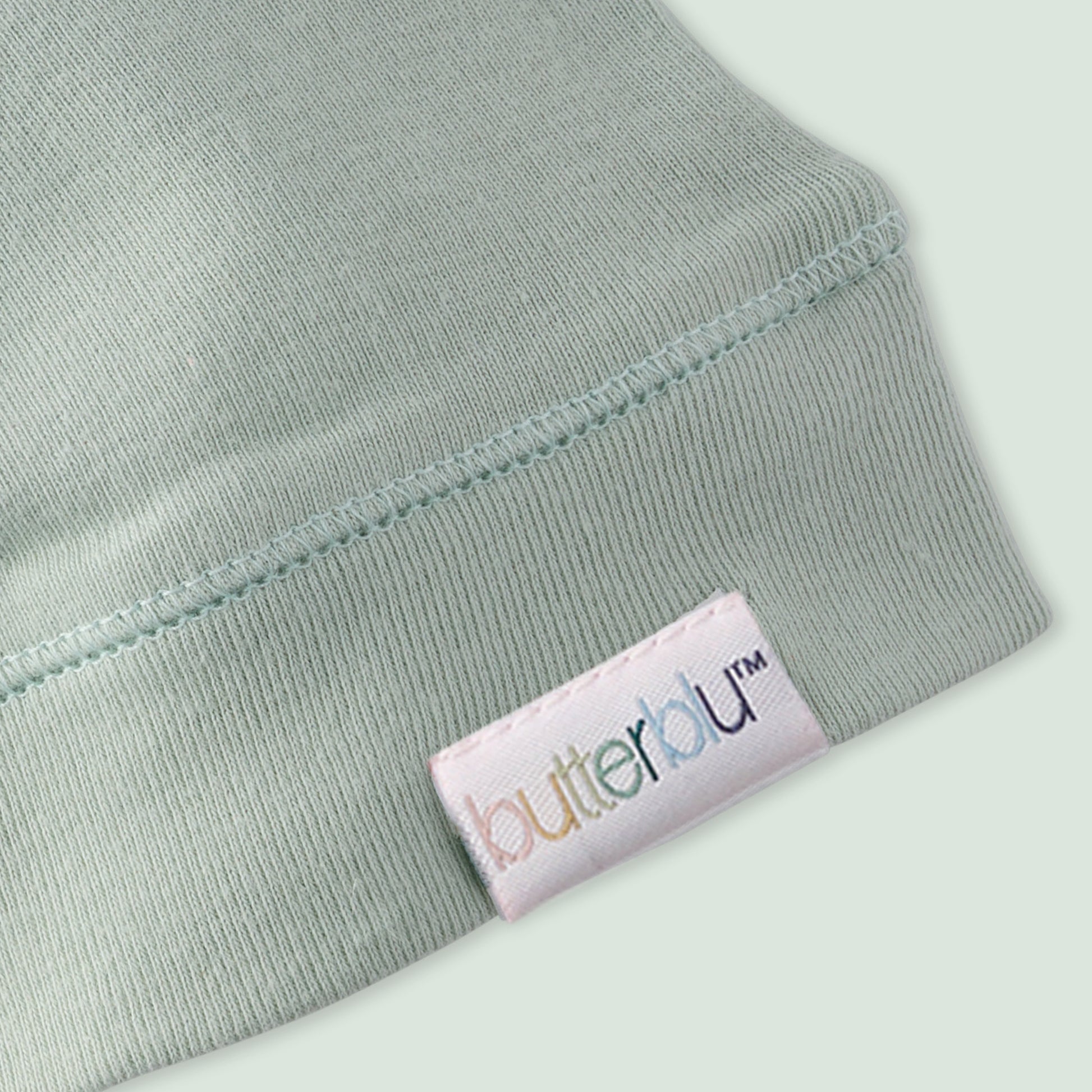 Close-up of a light green fabric with a 'butterblu' label on a white background