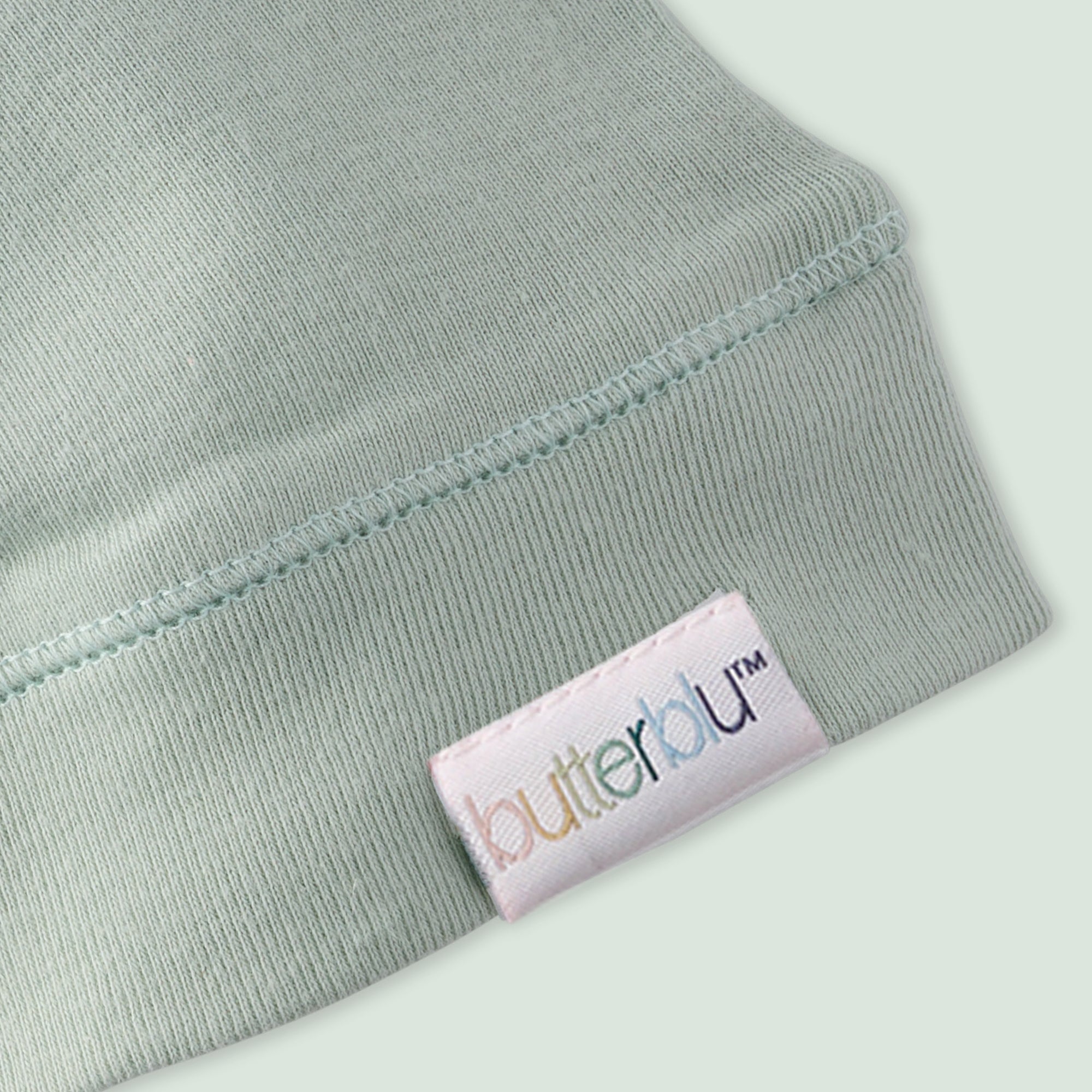 Close-up of a light green fabric with a 'butterblu' label on a white background