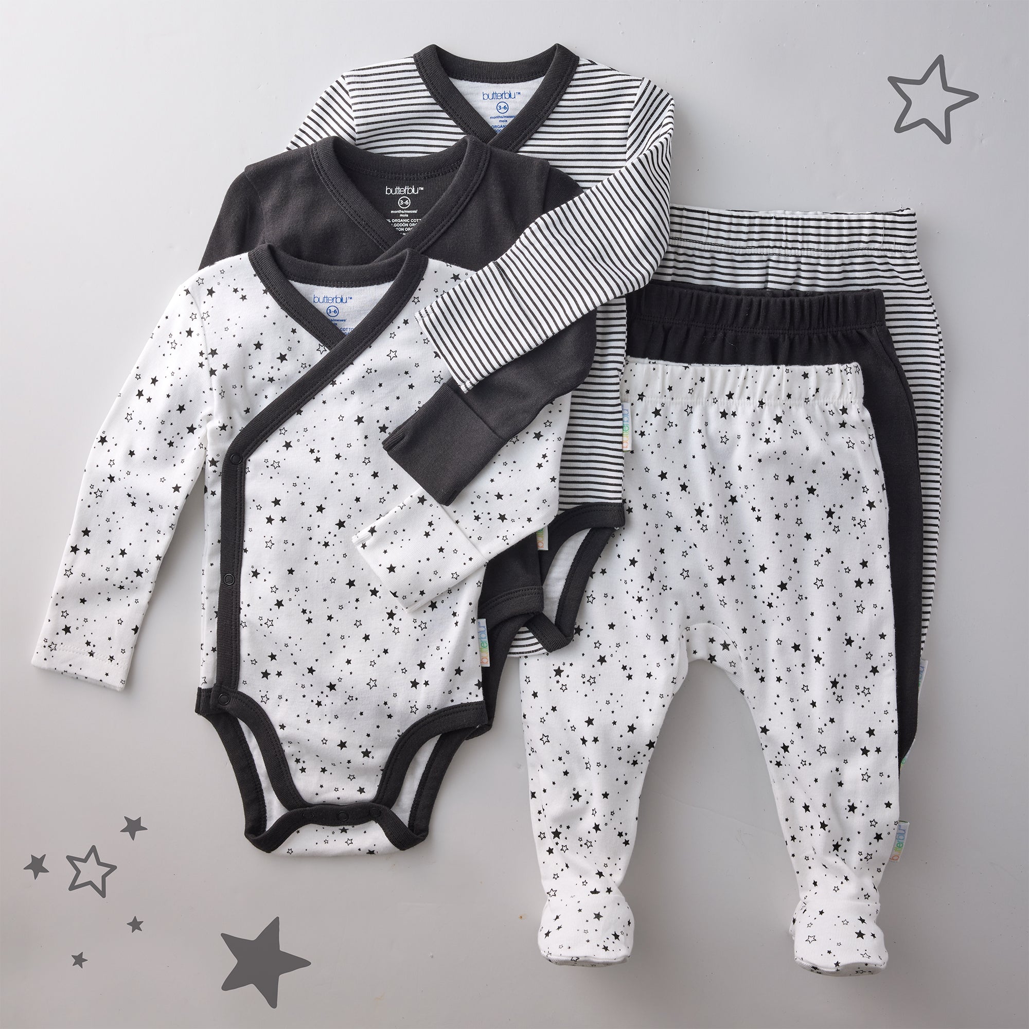 Baby clothing set with onesie, pants, and top on a gray background with star patterns