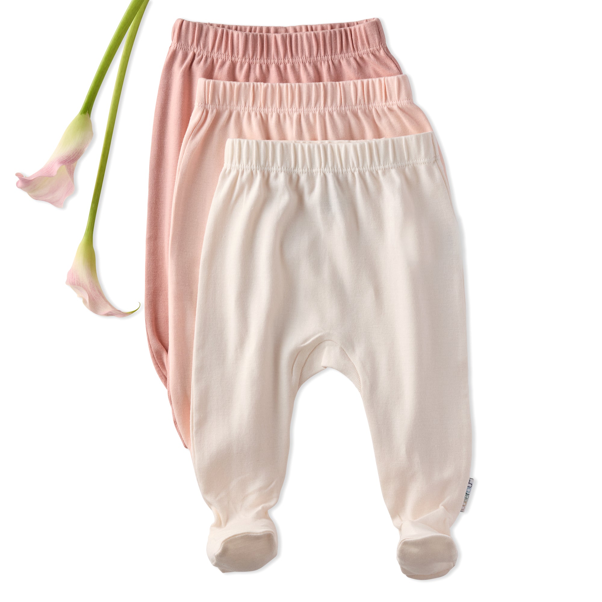 Three pairs of baby footed pants, one pink and one beige, on a white background with a flower.