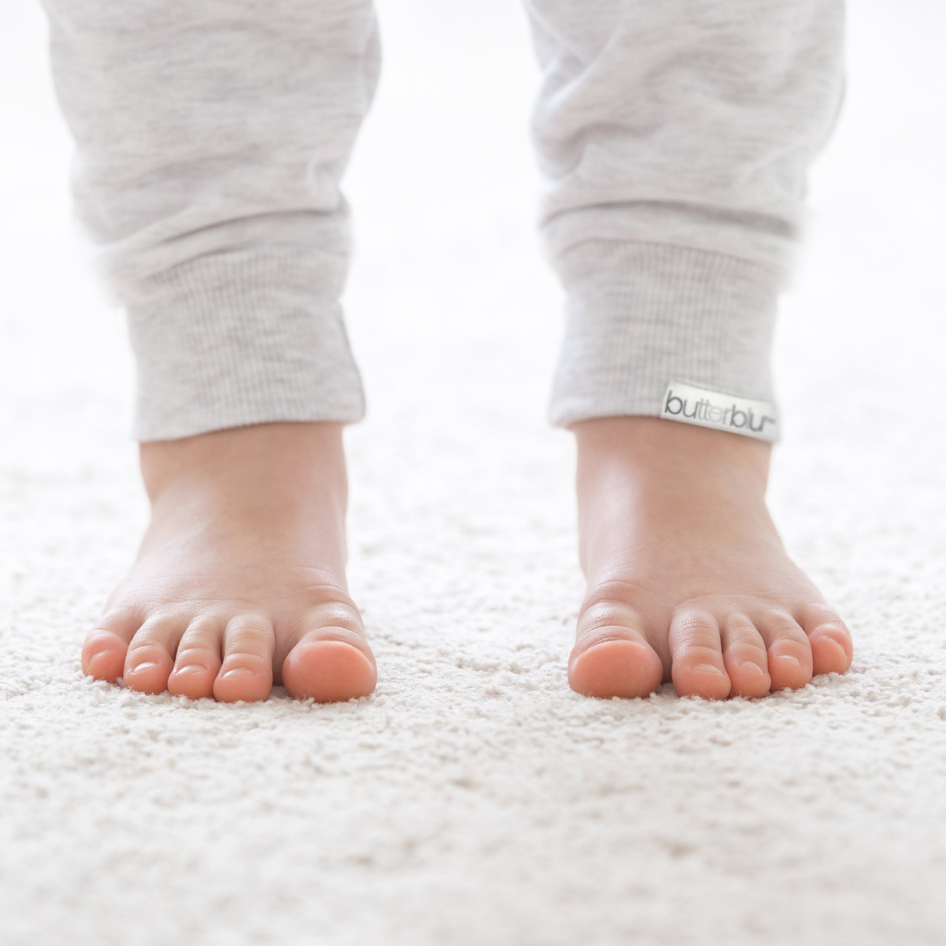 Baby's feet wearing gray socks with a visible brand logo on a white background