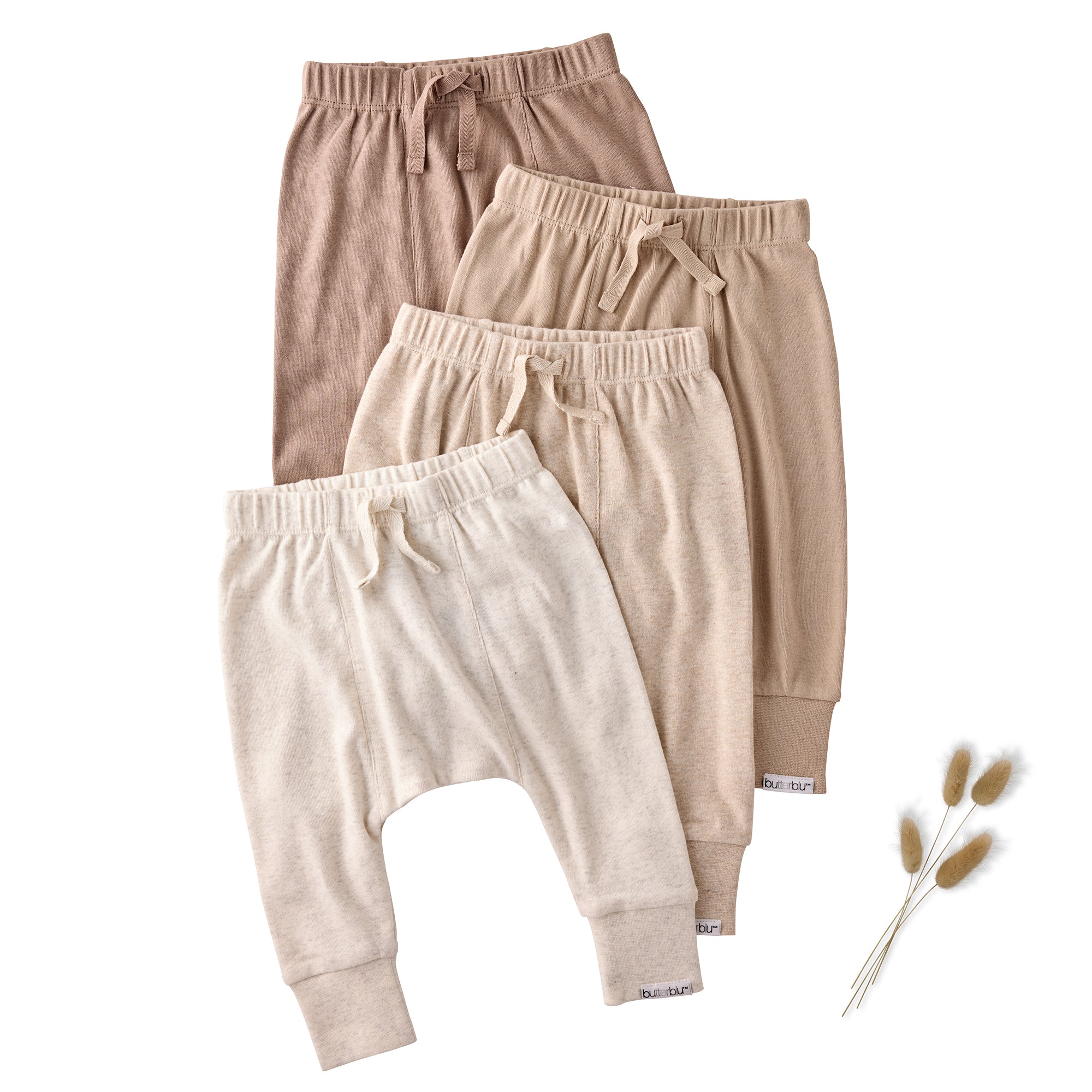 Three pairs of kids pants in beige, brown, and white on a white background.