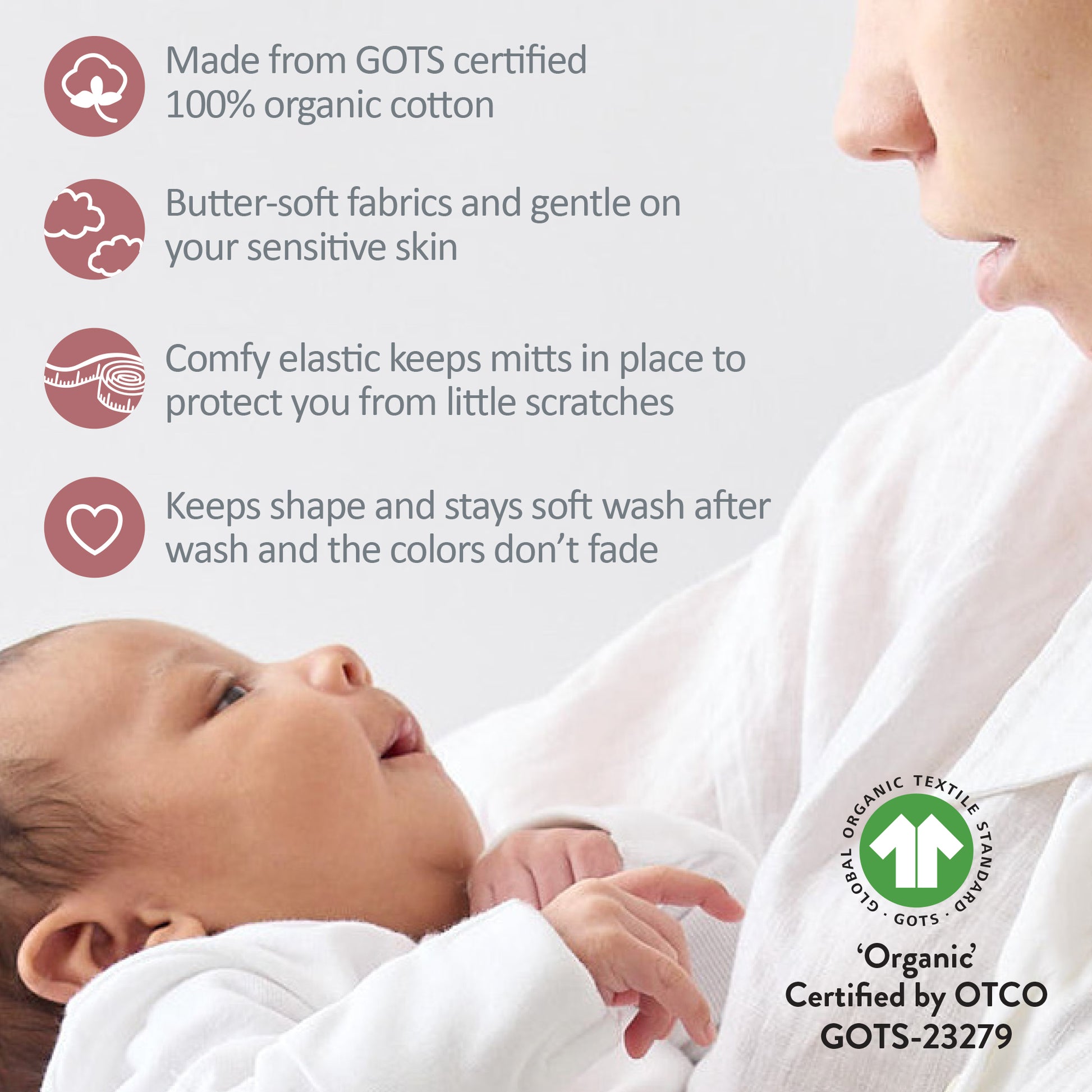 Baby wearing white organic cotton mittens with a mother holding the baby, featuring GOTS certification.