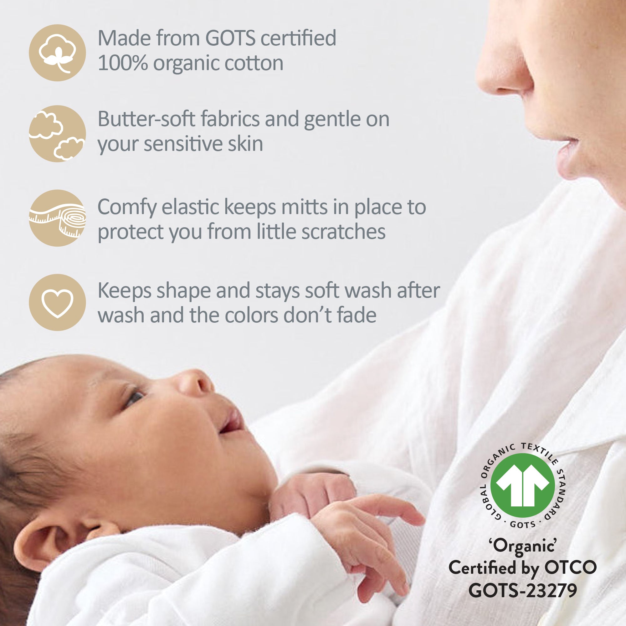 Baby wearing white organic cotton mittens with a mother holding them, featuring GOTS certification.