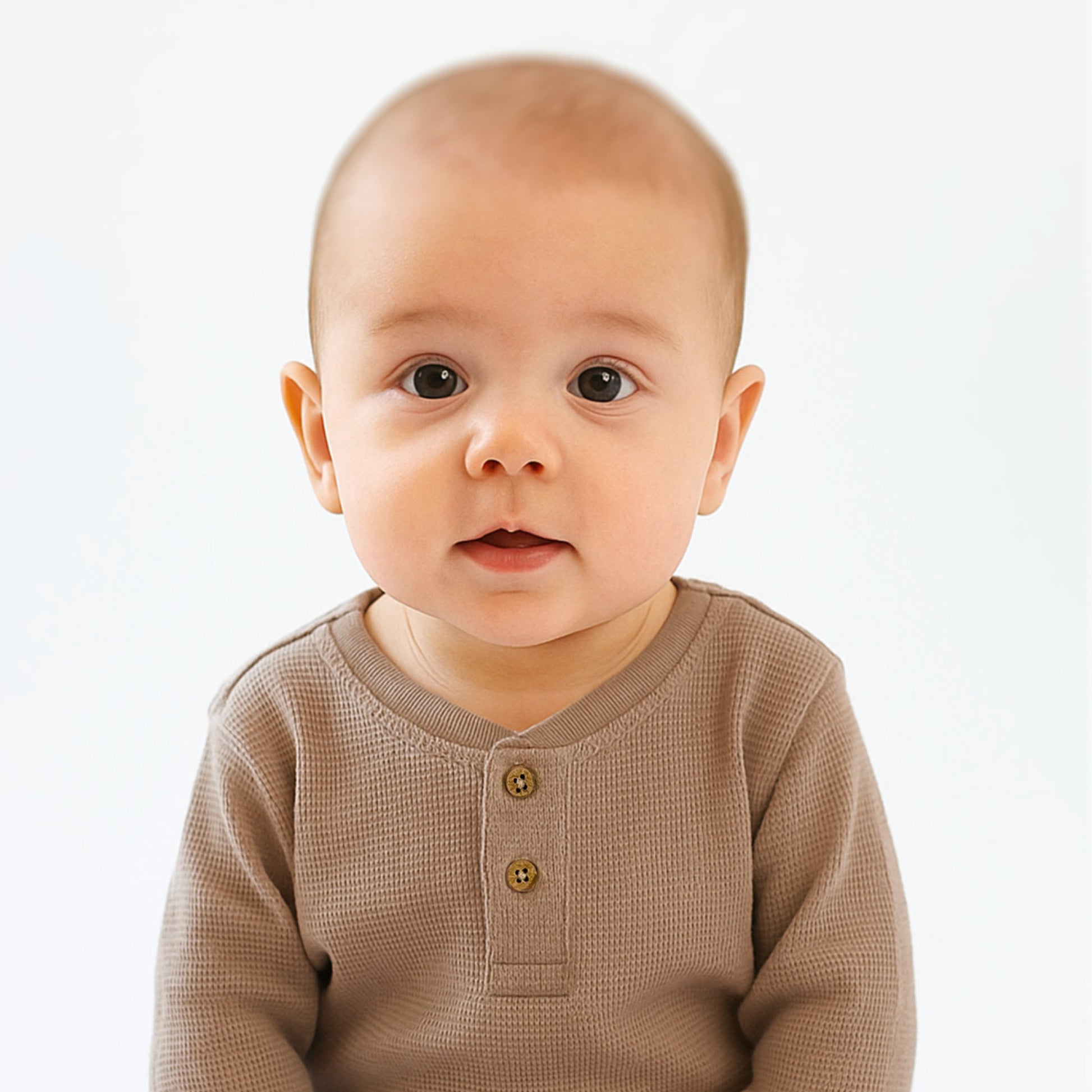 Baby wearing a brown long-sleeve shirt on a white background