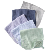 Set of five muslin burp cloths in various colors on a white background