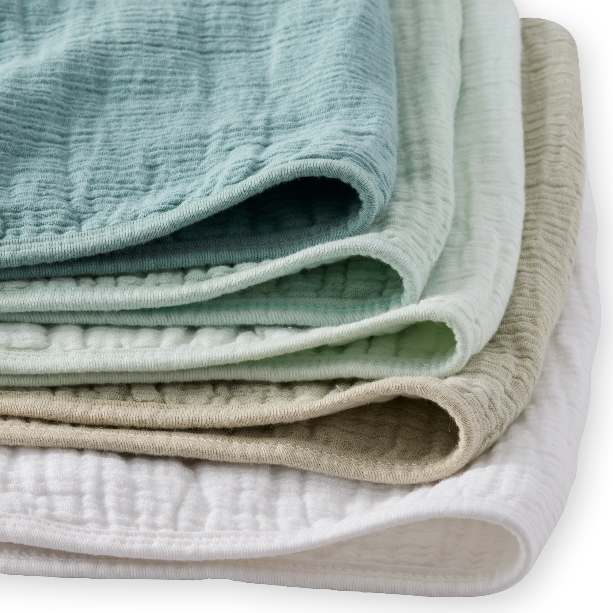Stack of folded textured fabric sheets in green, beige, and white on a white background