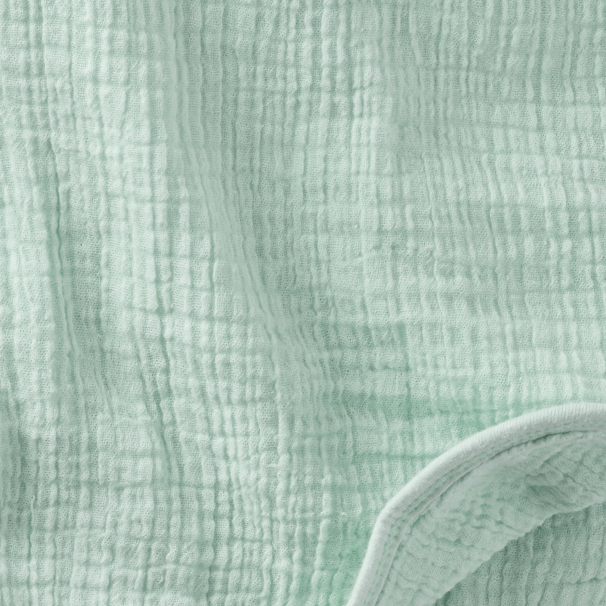 Close-up of textured light green fabric with a slight sheen.