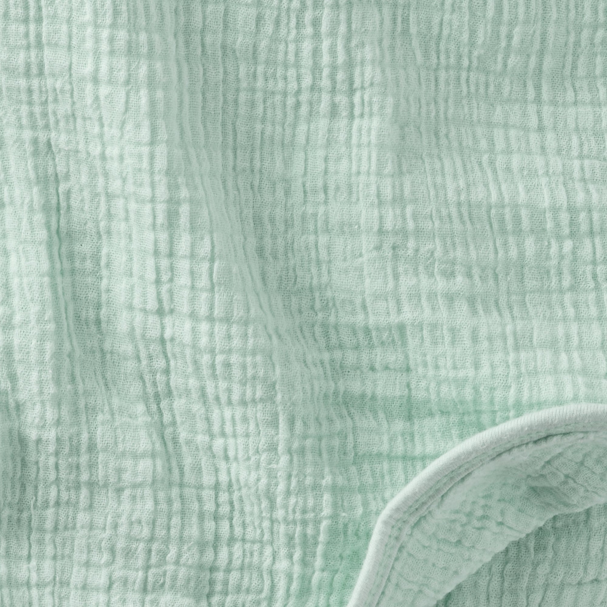 Close-up of textured light green fabric with a slight sheen.