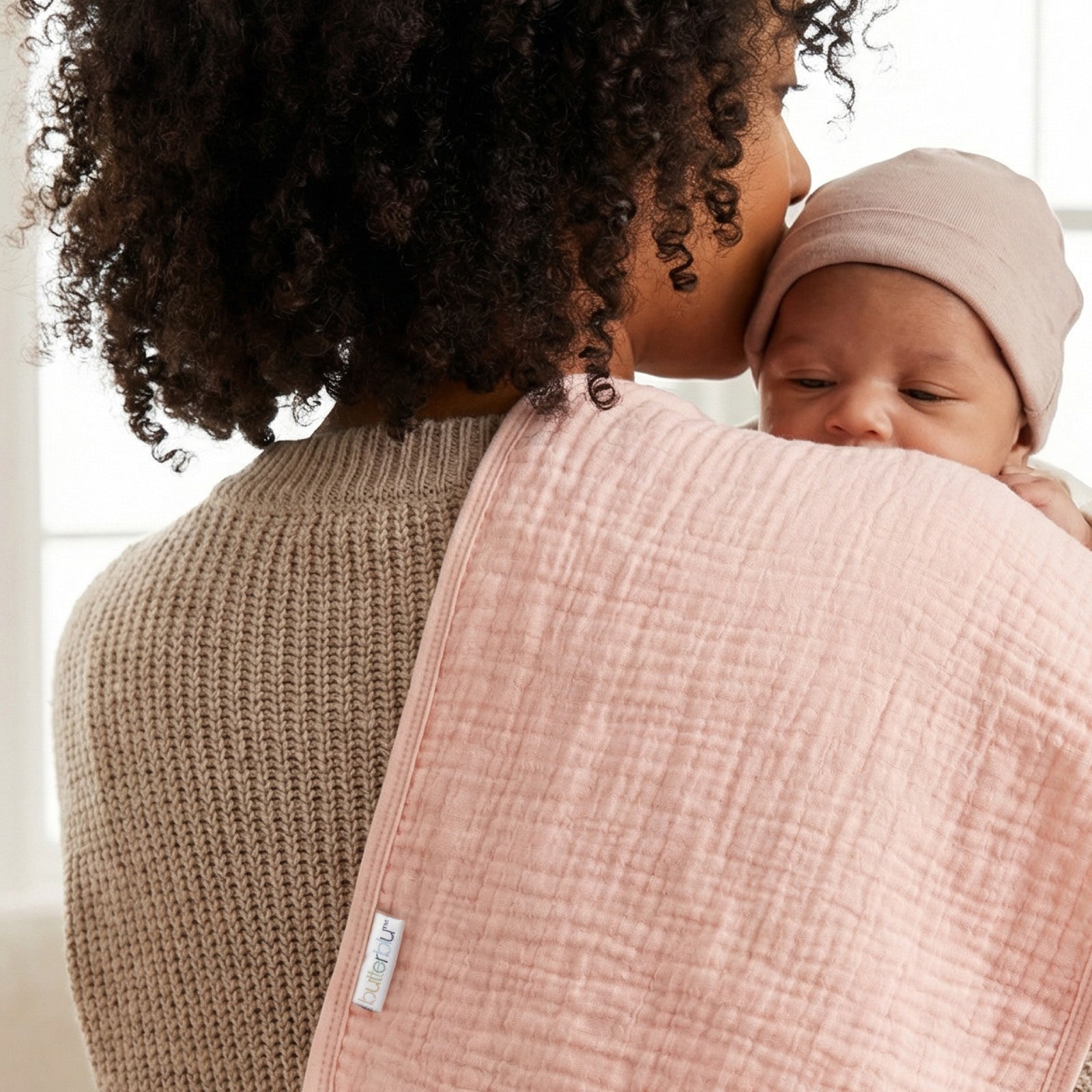Woman holding a baby with a pink burp cloths  with a blurred background