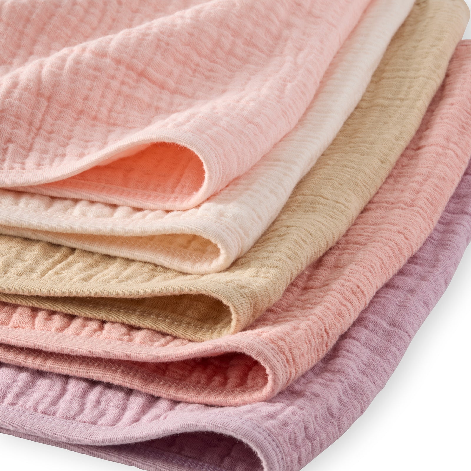 Stack of folded textured fabric in pink, beige, and purple on a white background