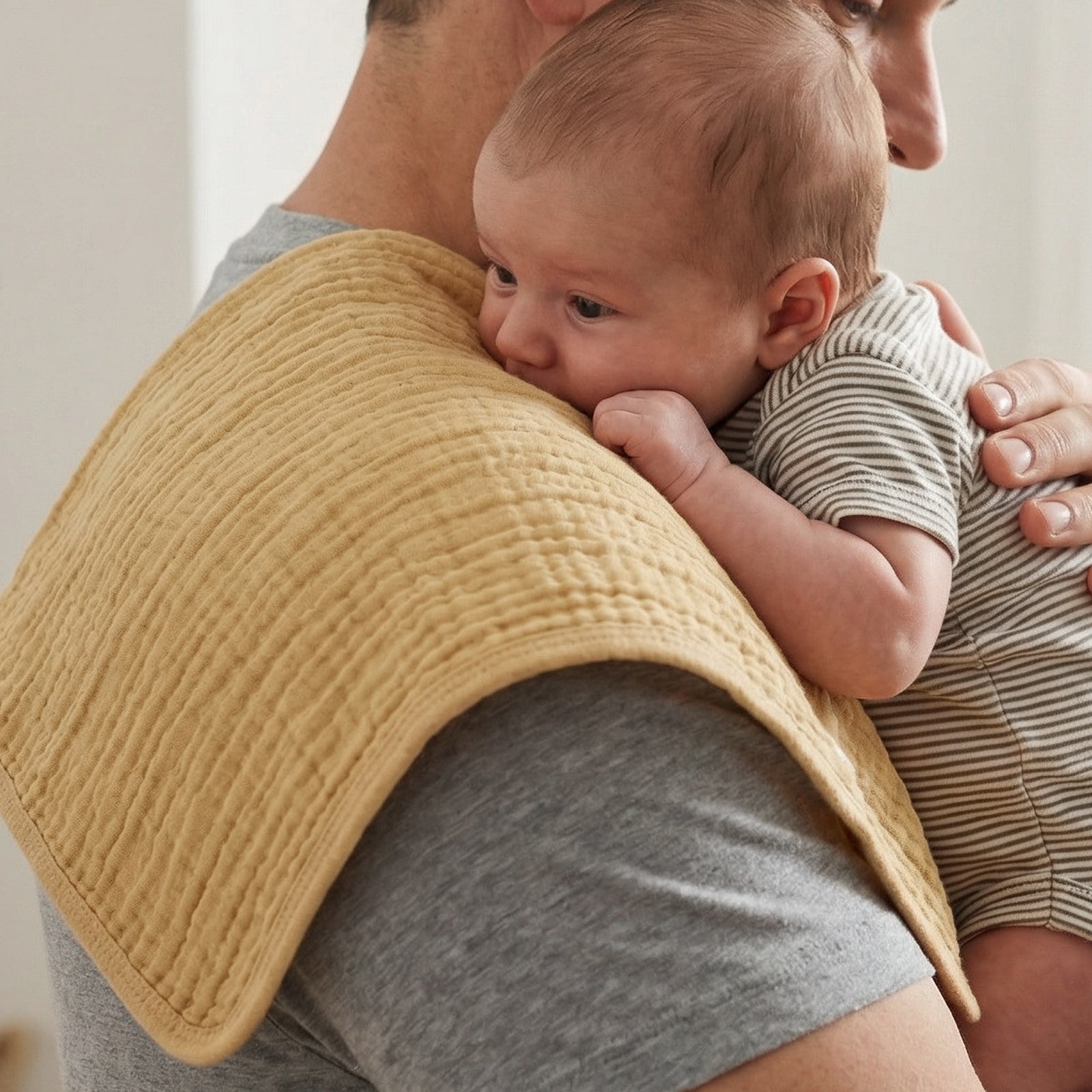 Person holding a baby wrapped in a yellow blanket