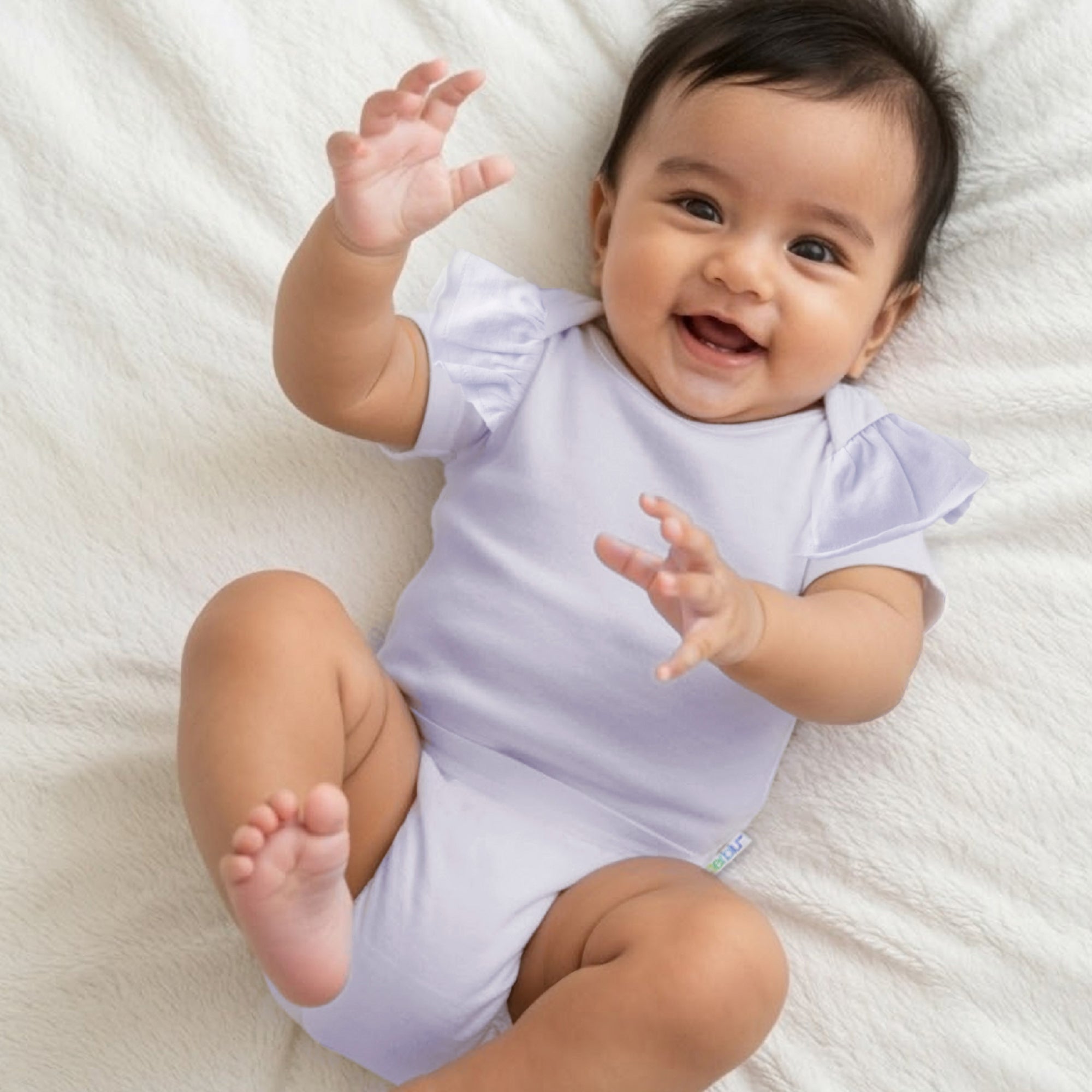Baby in a light purple onesie lying on a white blanket