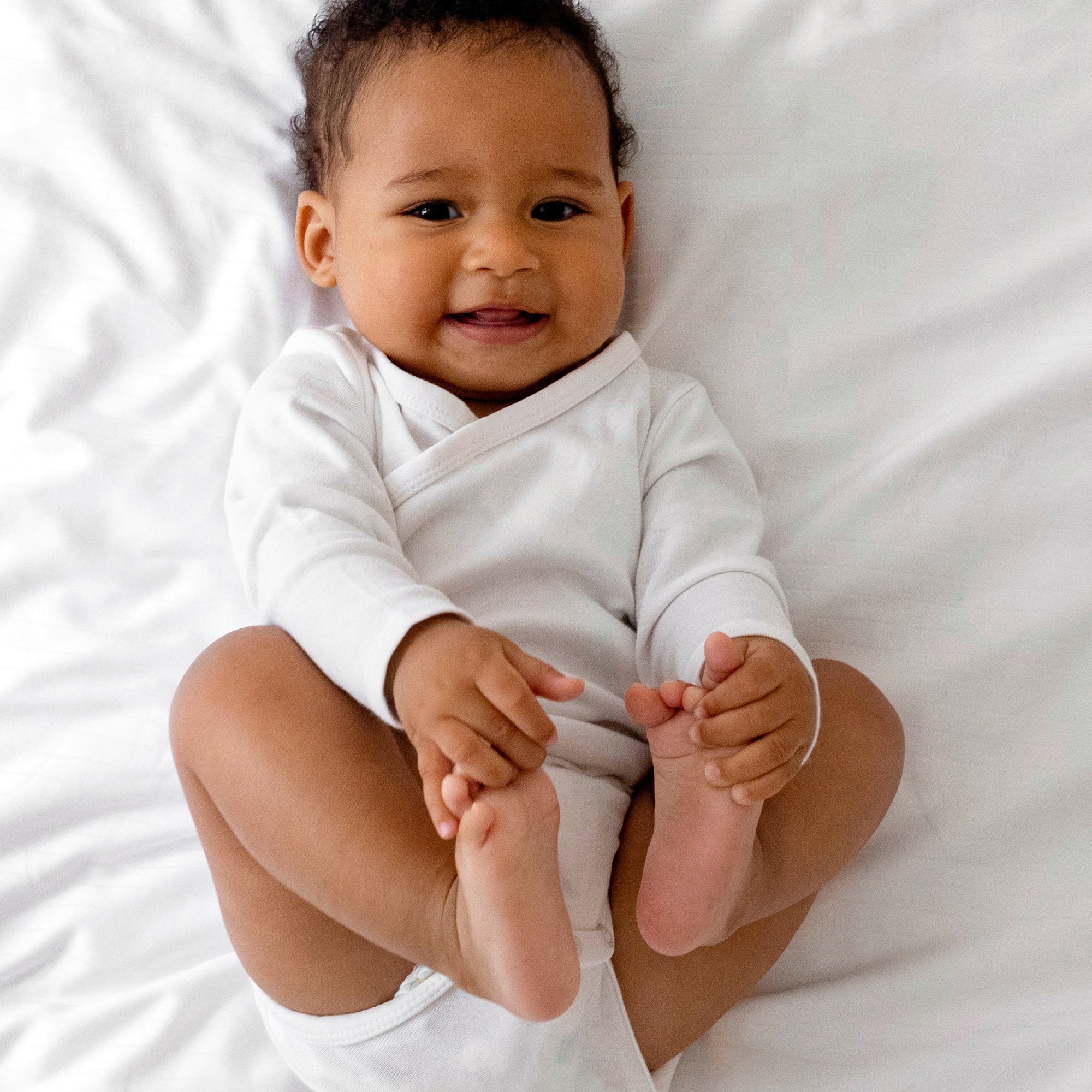 Baby in a white onesie lying on a white surface
