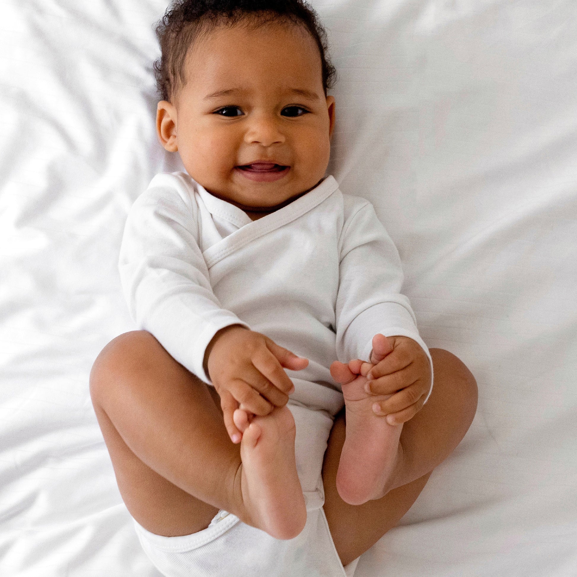 Baby in a white onesie lying on a white surface